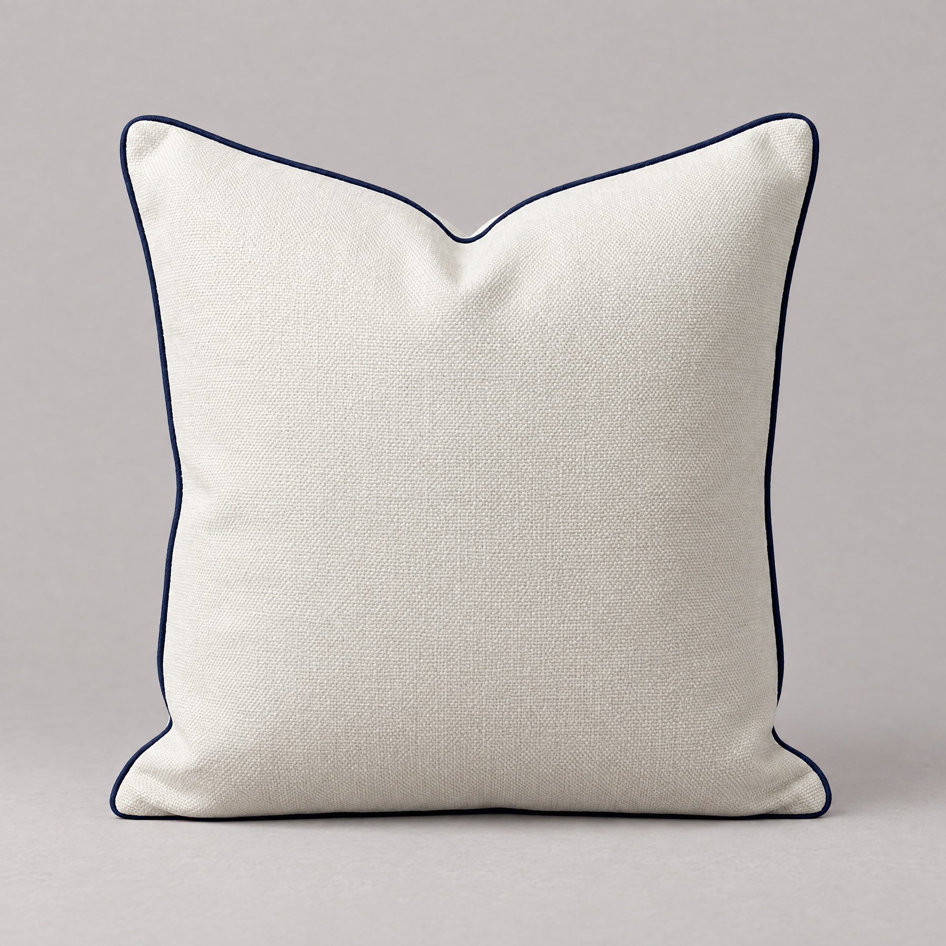 Ivory linen square Vedado throw pillow with navy piping on a neutral background.