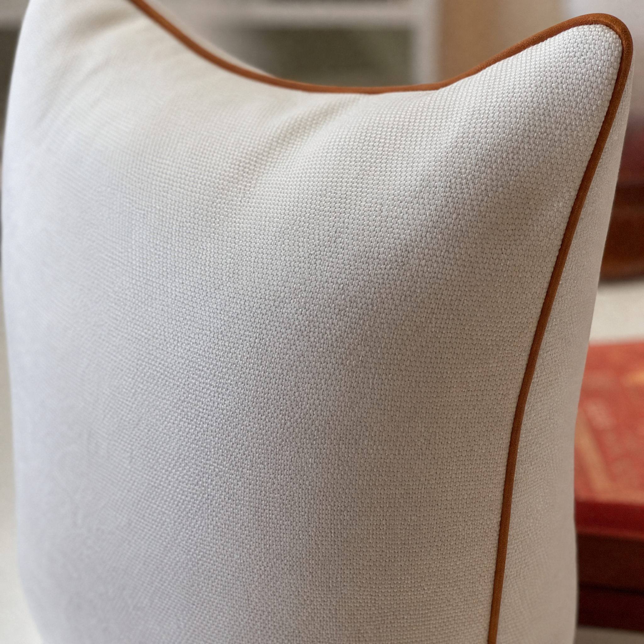Close-up of textured ivory linen Vedado pillow with a thin cognac edge.