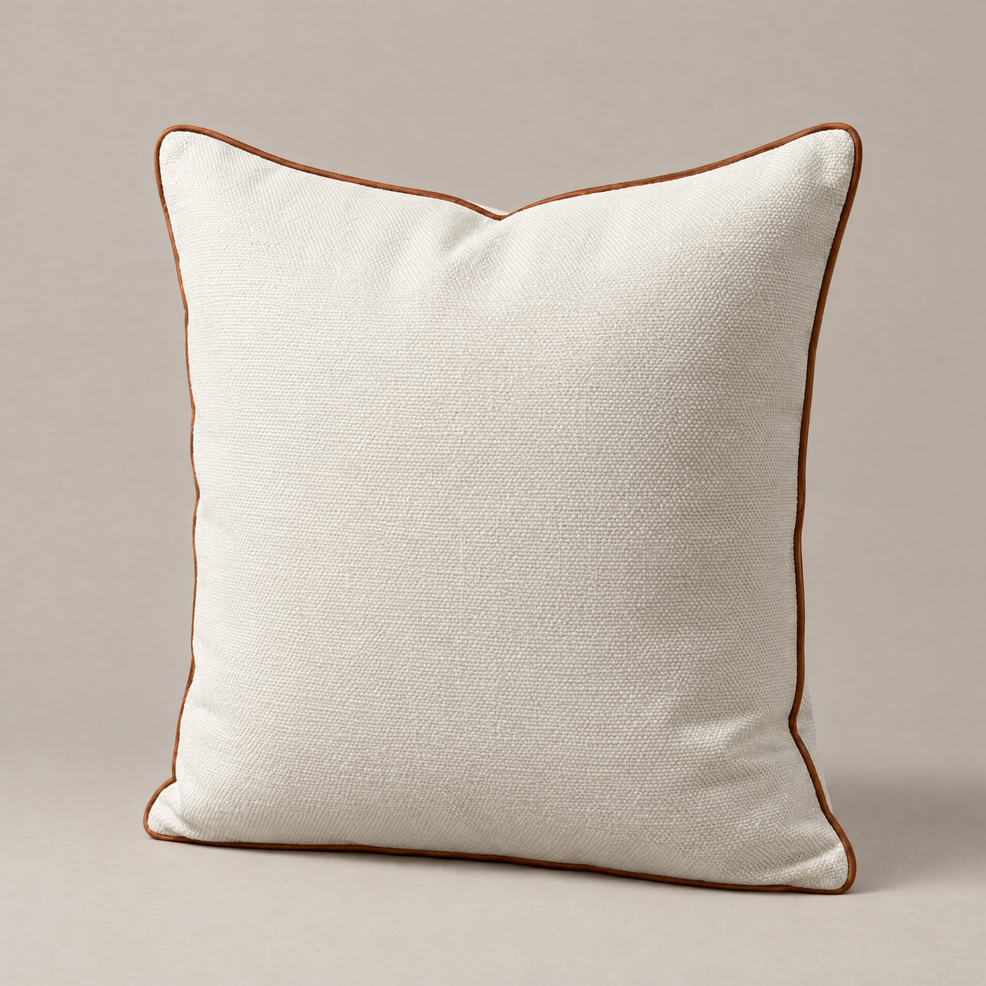 Ivory linen square Vedado pillow with brown piping on a plain light background.