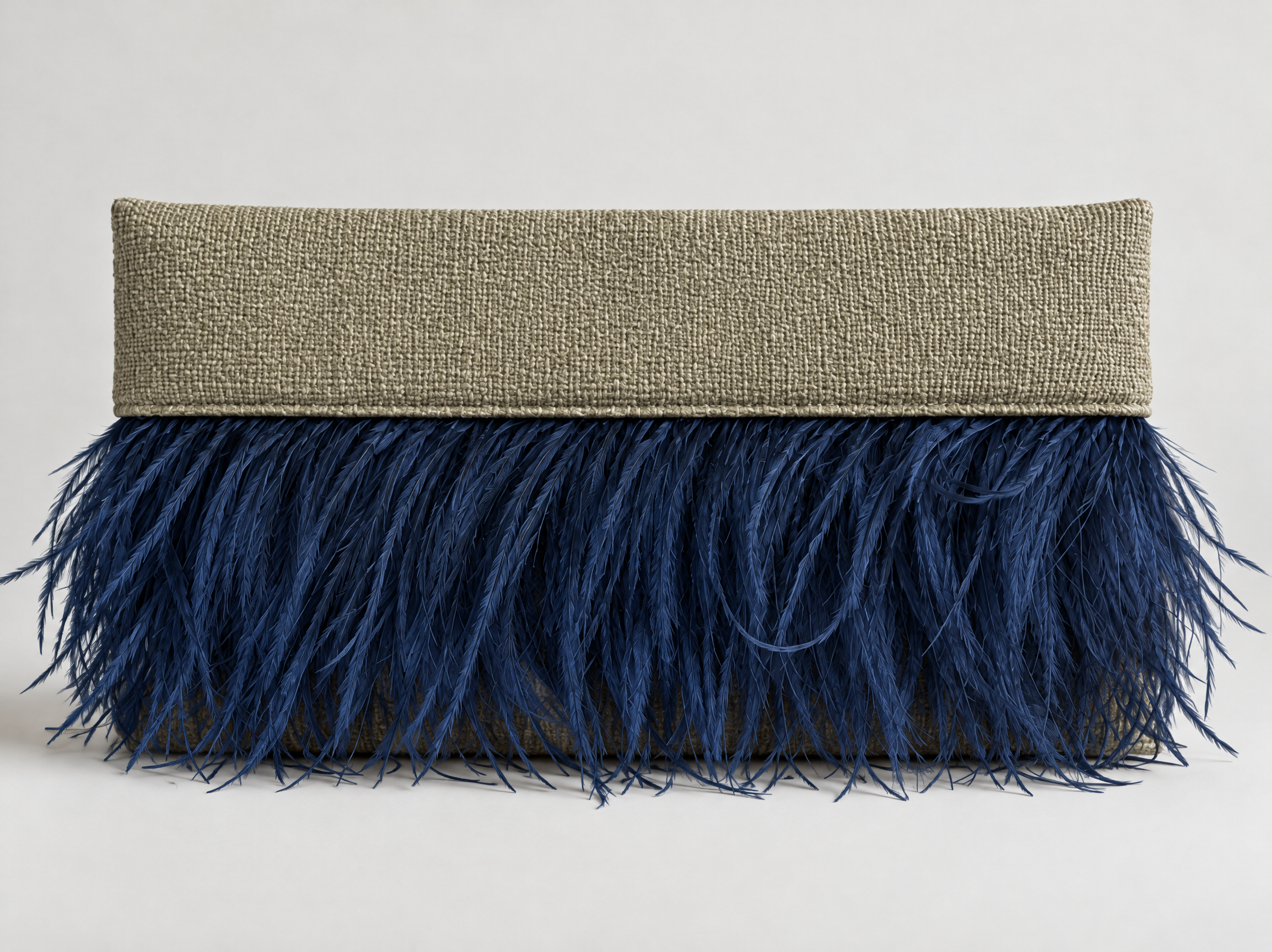 Close-up of a square-shaped decorative pillow with a beige woven fabric top and a bottom part covered in dark blue feathers, placed against a plain white background.