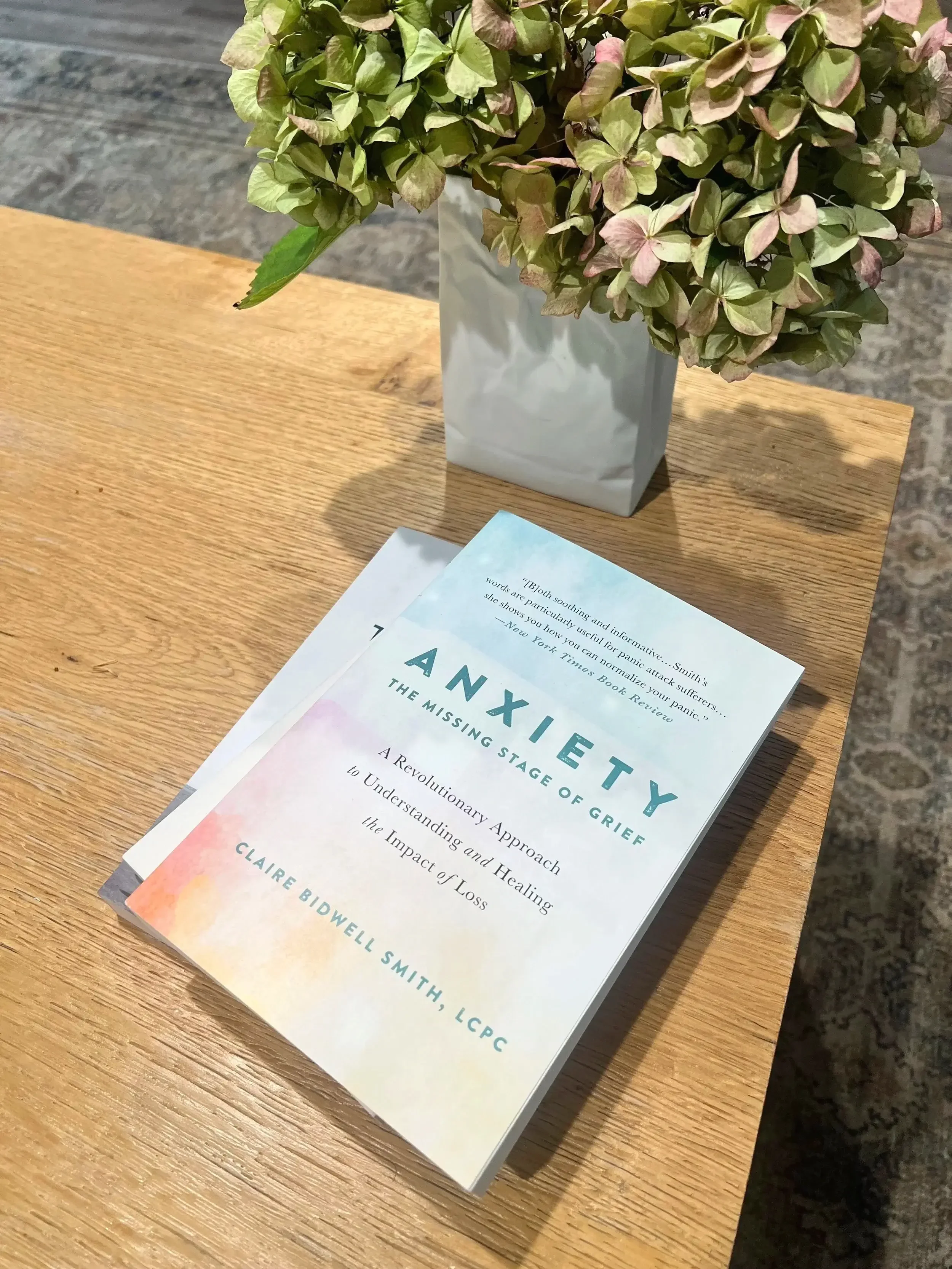 therapy office desk with vase of hydrangeas and book on anxiety