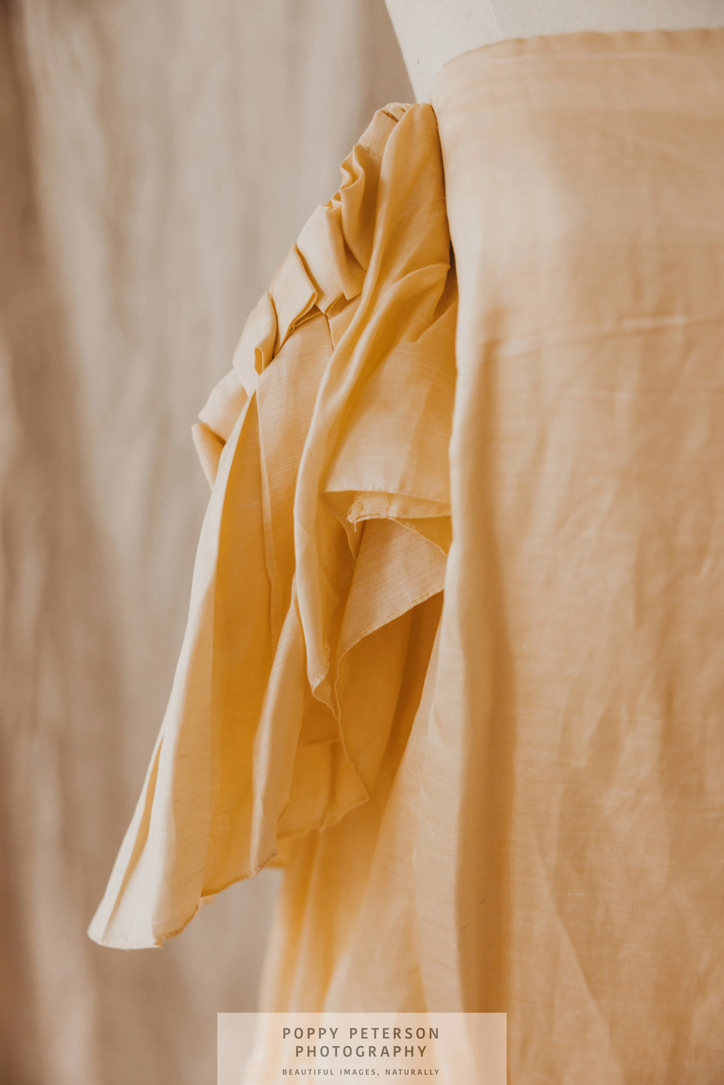 Close-up of hanging beige and yellow clothing or fabric on a display hook.