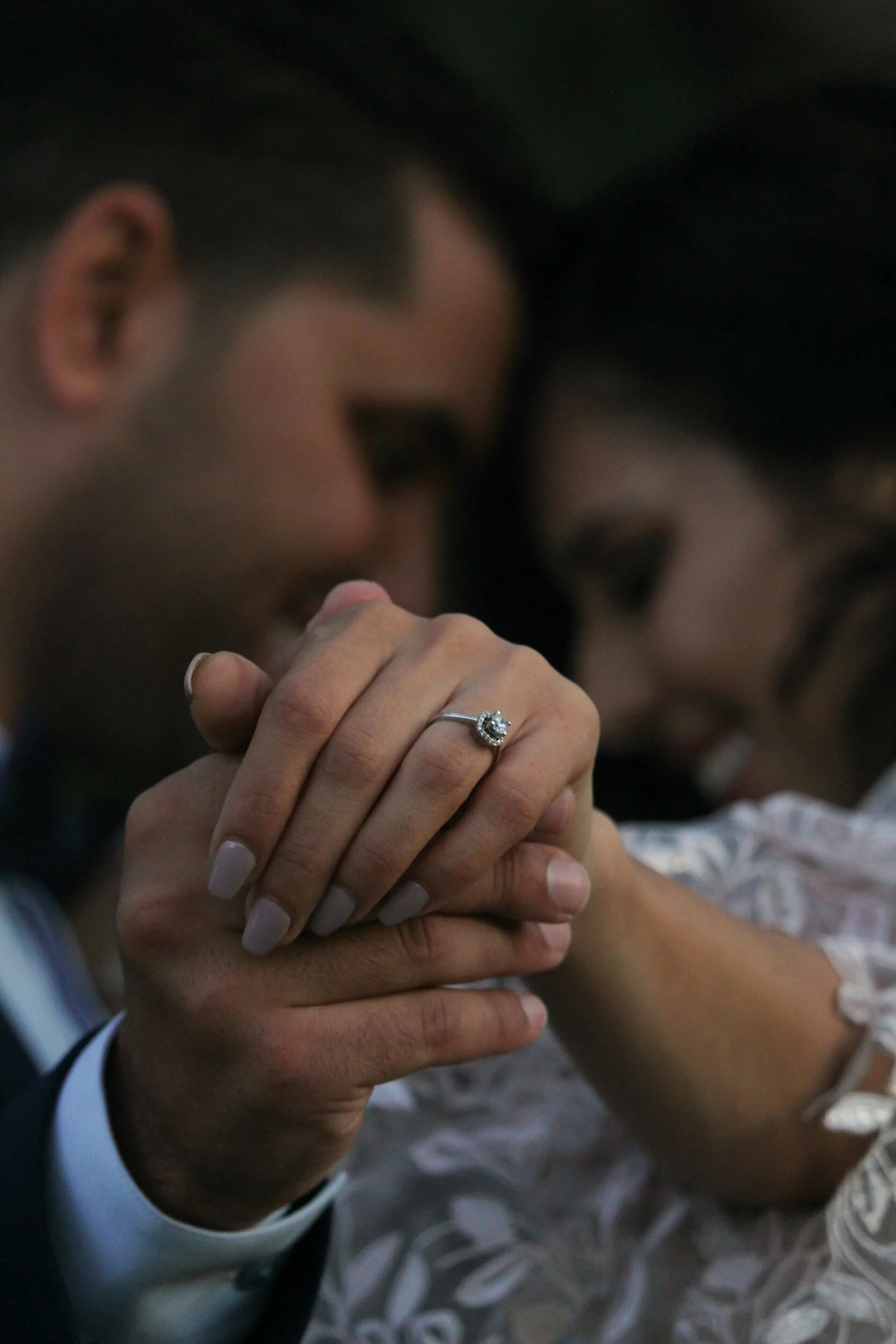 A couple holding hands, with the woman showing a diamond engagement ring on her finger.