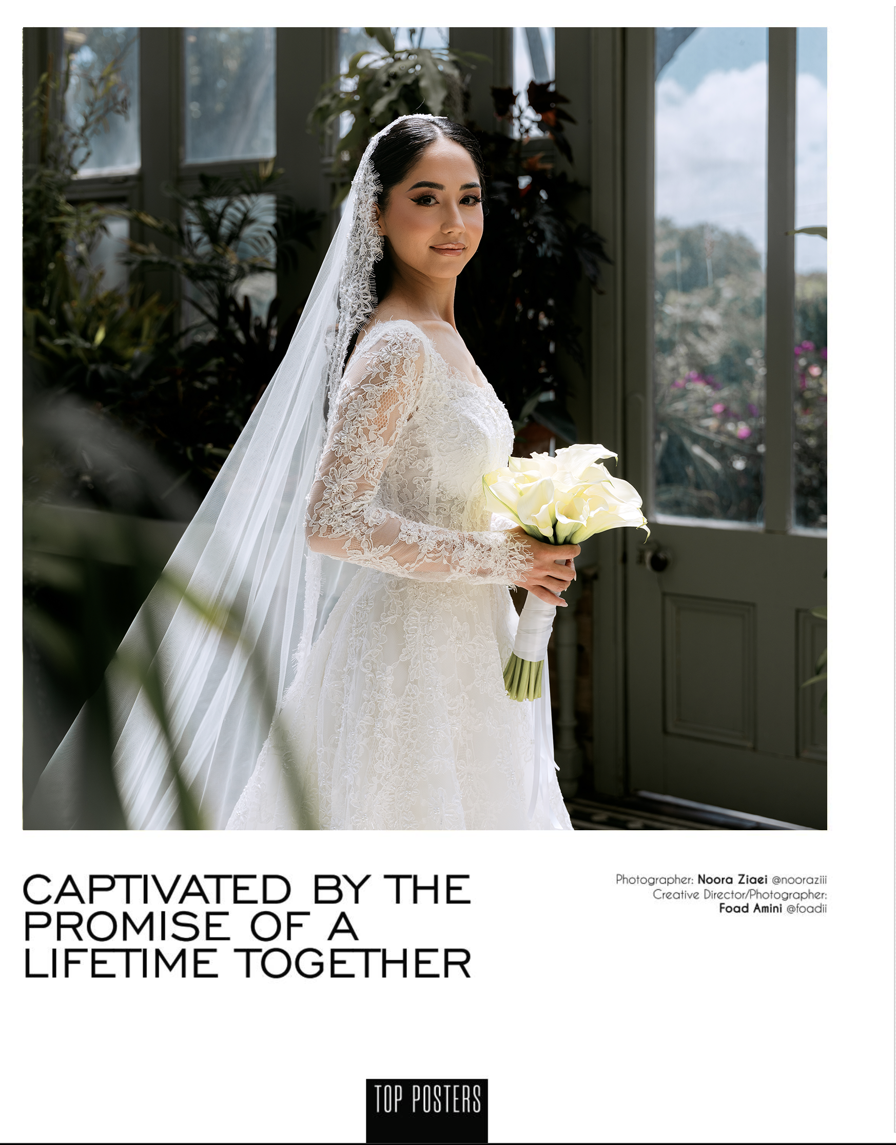 A bride in a lace wedding dress with a veil standing indoors, holding a bouquet of white calla lilies, with large windows and plants in the background.