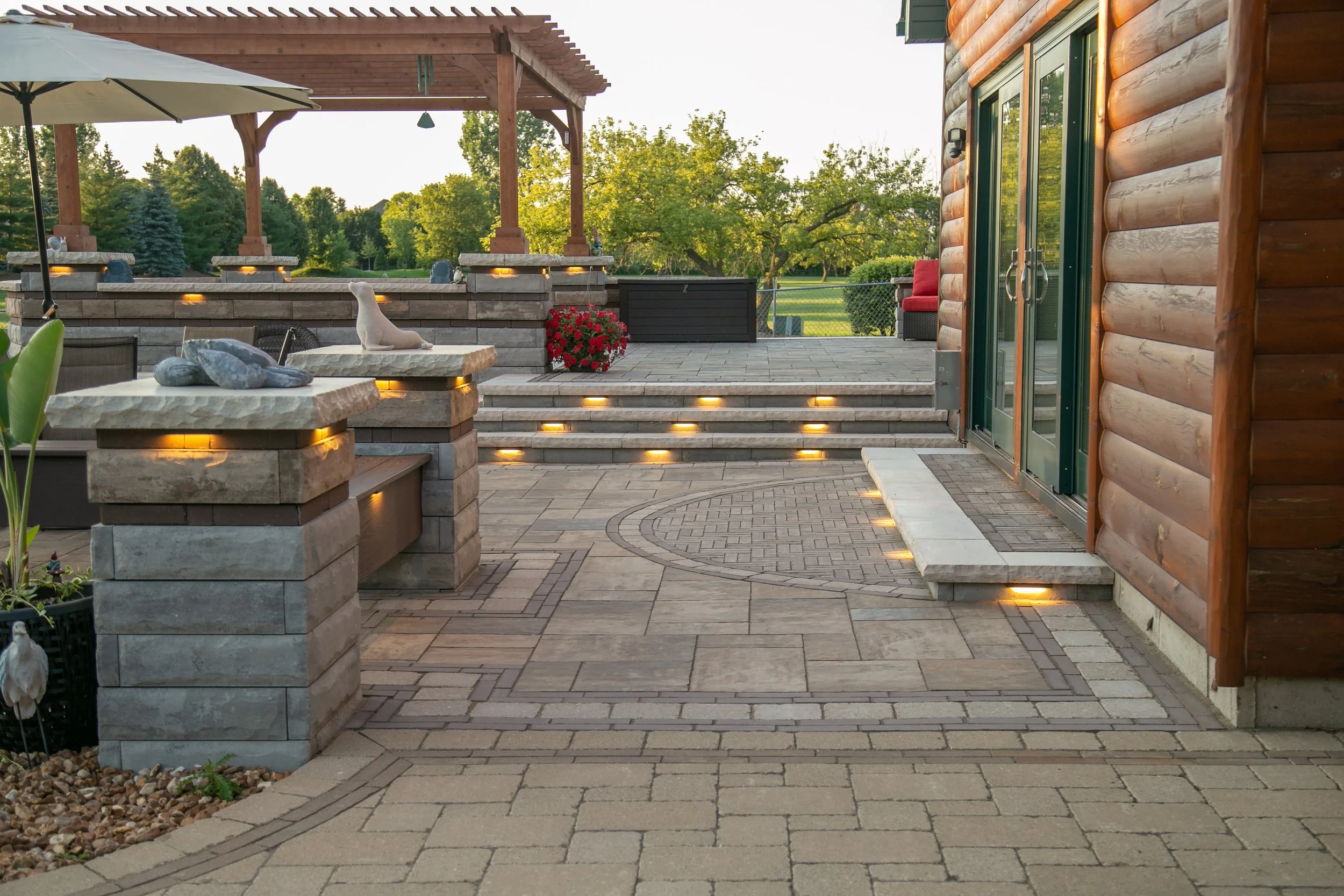 Beautiful paver patio with stone steps, wooden pergola, and lighting