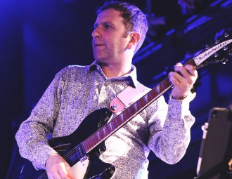 A man playing an electric guitar on stage during a performance.