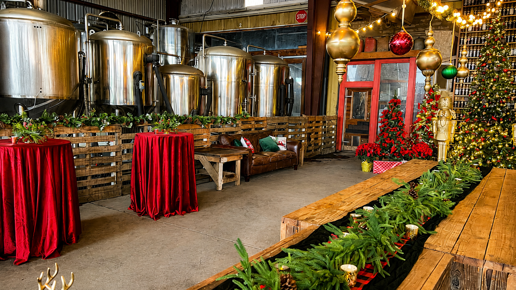 Red velvet cocktail tables with holiday greenery centerpieces inside a decorated industrial event venue.
