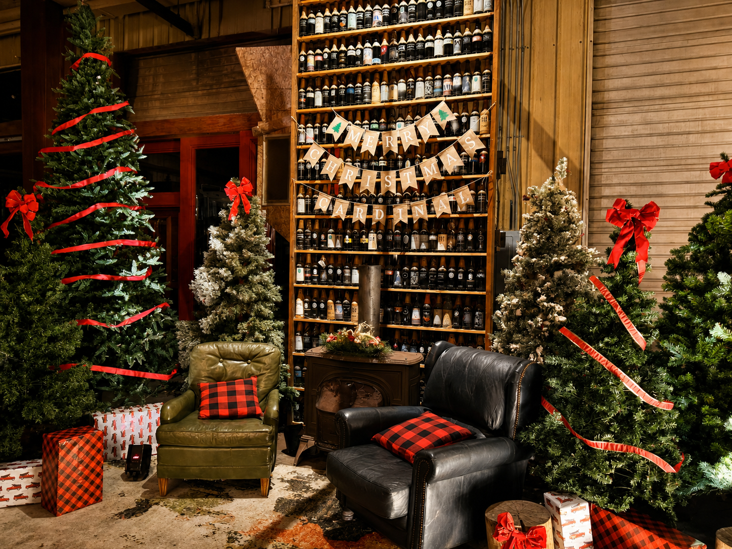 A cozy holiday lounge featuring Christmas trees, buffalo plaid accents, wrapped gifts, vintage-style seating, and rustic décor creates an inviting space for guests to gather.