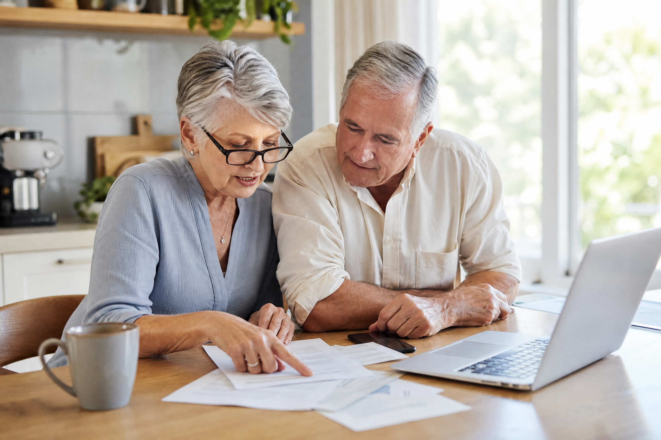 Couple in their 60s reviewing Medicare enrollment and HSA paperwork together at kitchen table