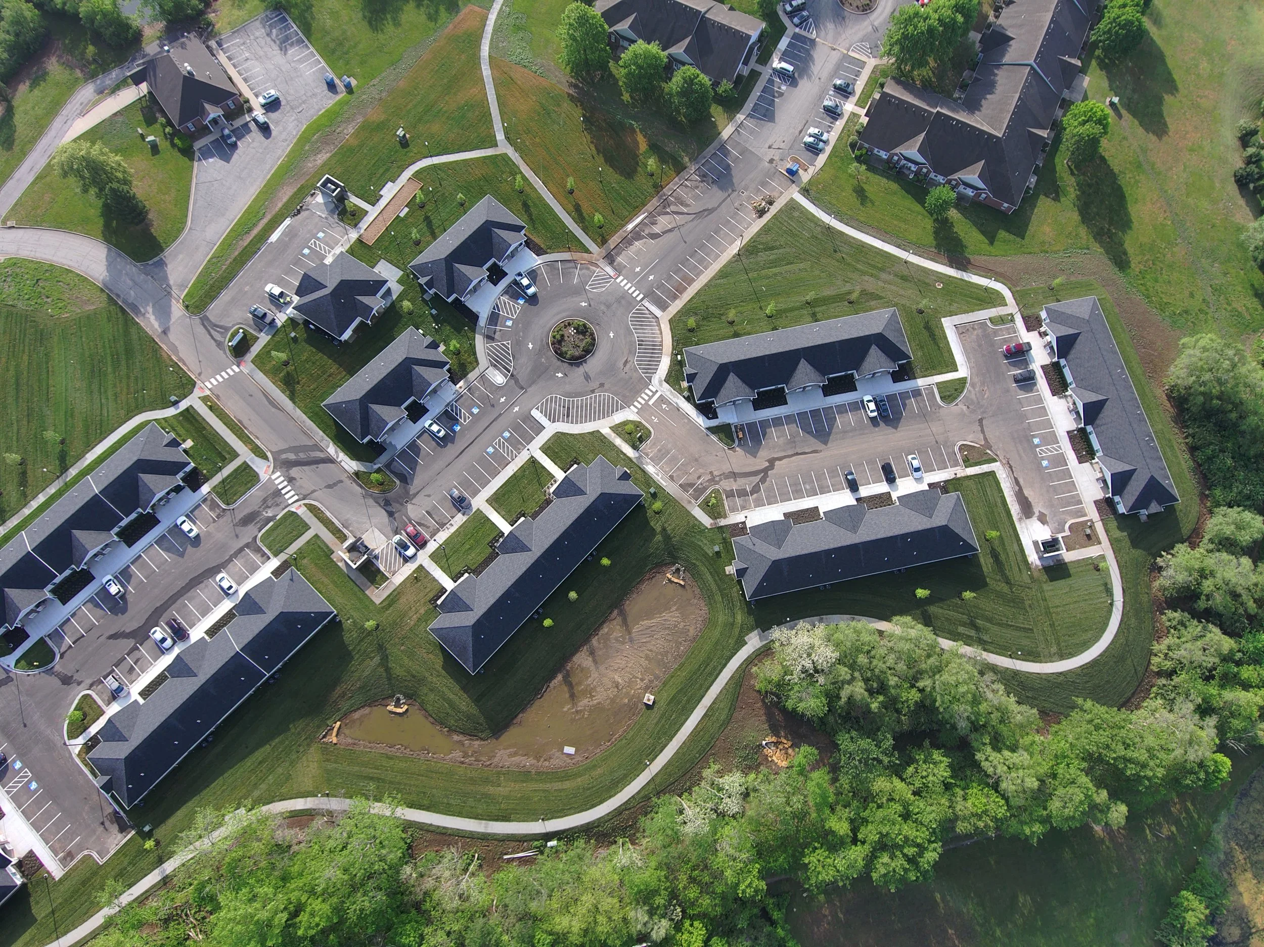 Aerial view of a multi-building residential development featuring landscaped grounds, parking areas, and walkways, illustrating the scale of architectural design projects.