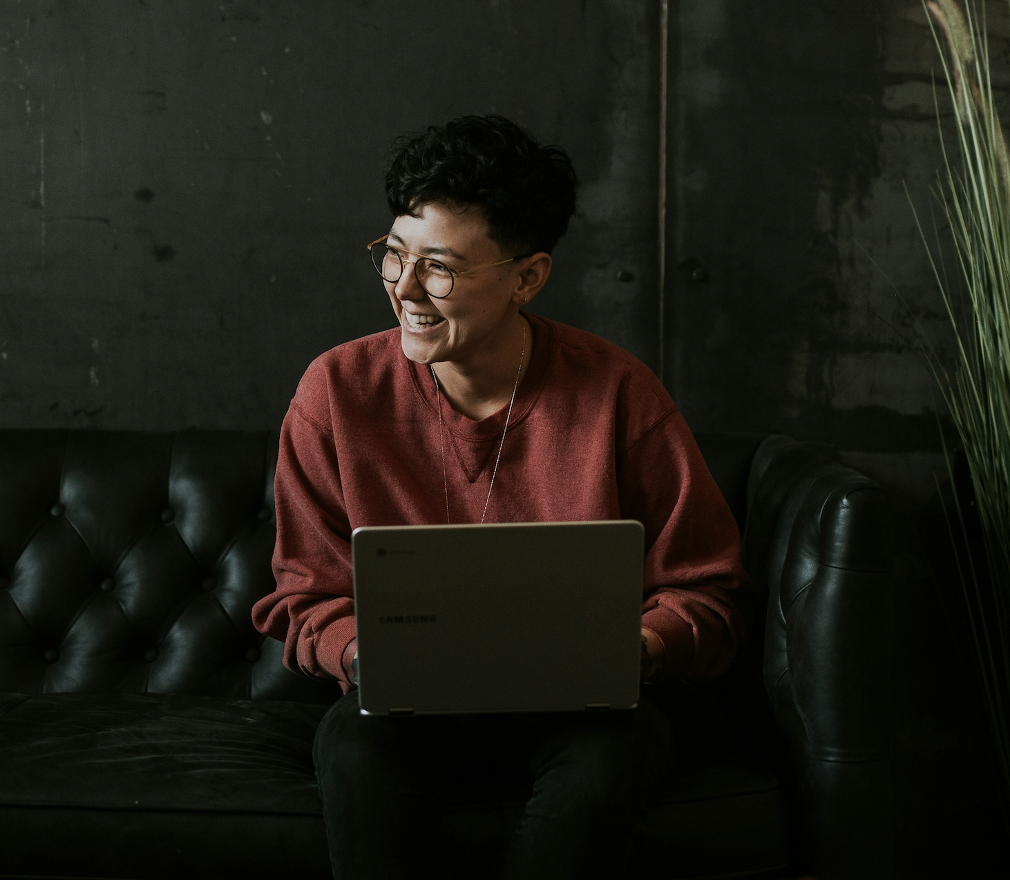 Person with glasses smiling with laptop looking happy and alcohol free