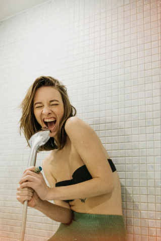 Woman taking a cold shower and laughing