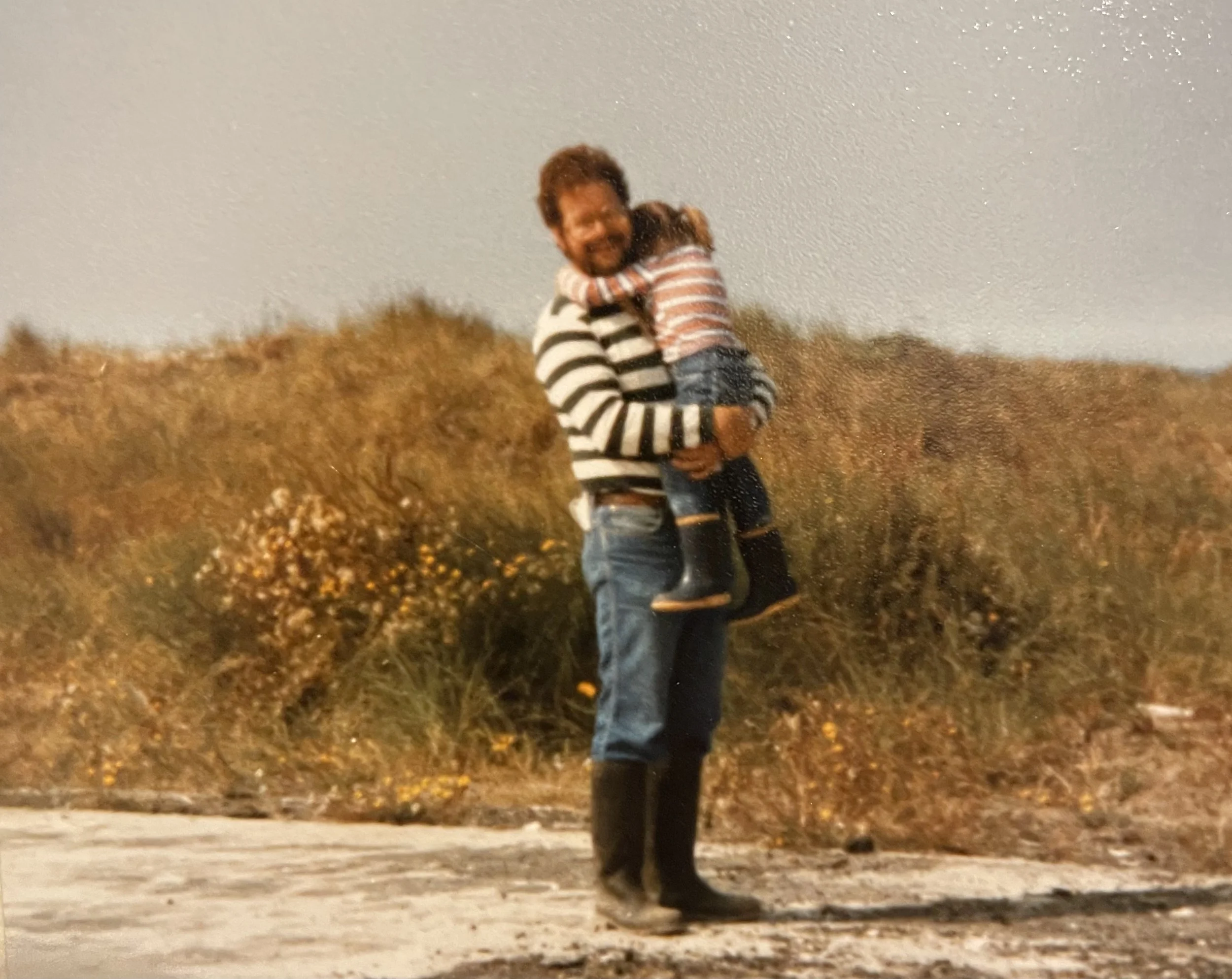 Image of a father holding a young daughter on the beach