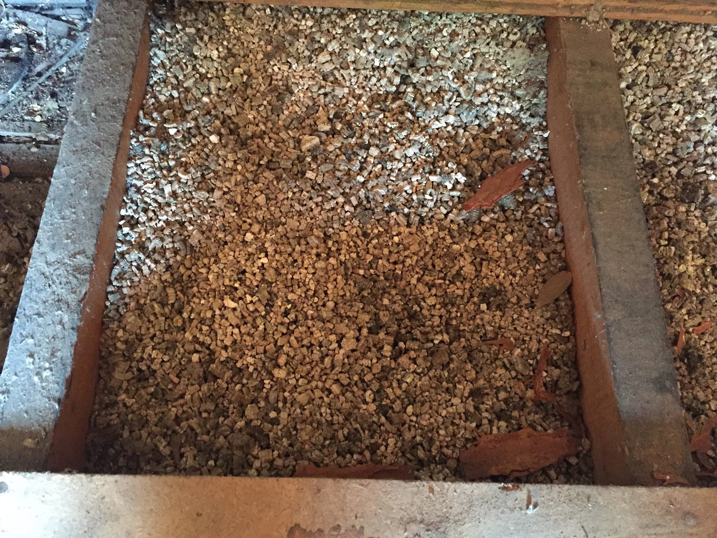 Pebble-like vermiculite attic insulation with a metallic, accordion-style texture.