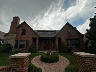 A custom brick residential home undergoing an intrusive asbestos inspection and material testing before permit submission for a major addition or remodel.