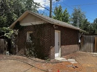 A red brick residential garage in Denver, Colorado, being evaluated during a pre-demolition asbestos inspection to test suspect materials like window glazing, door caulking, and roofing materials.