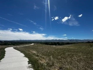 A paved walking path overlooking a field with the front range mountains in the background, representing the residential service area for asbestos testing in Lakewood, CO.