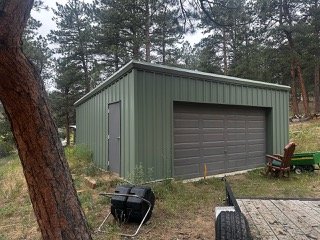 A green metal garage in Boulder, Colorado, undergoing a certified pre-demolition asbestos inspection to test panel adhesives, vapor barriers, and flashing sealants.