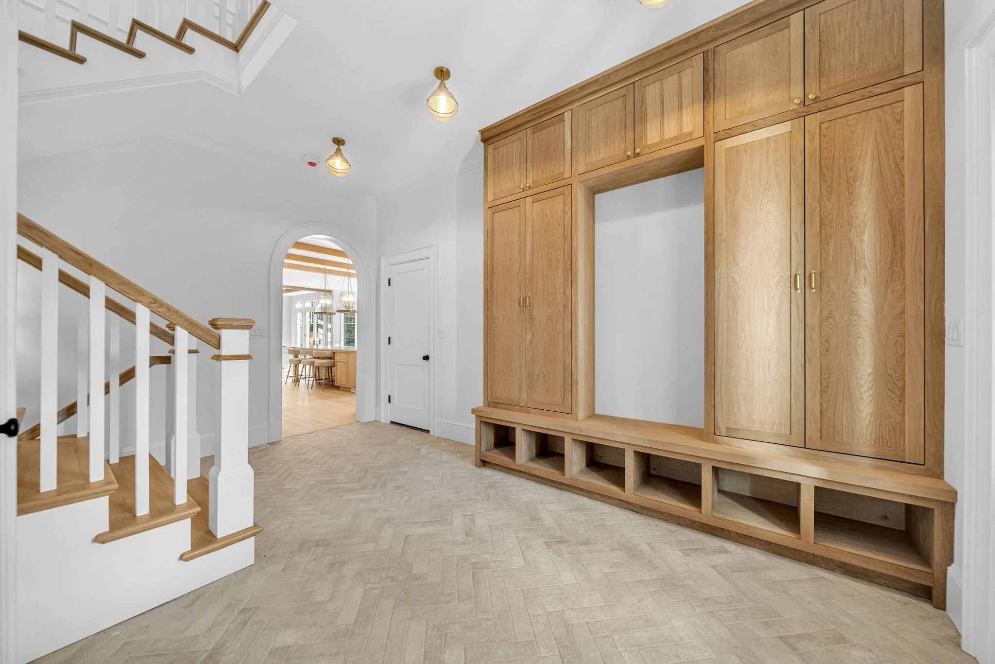 Entryway with built-in wooden storage, staircase, and view into dining area.