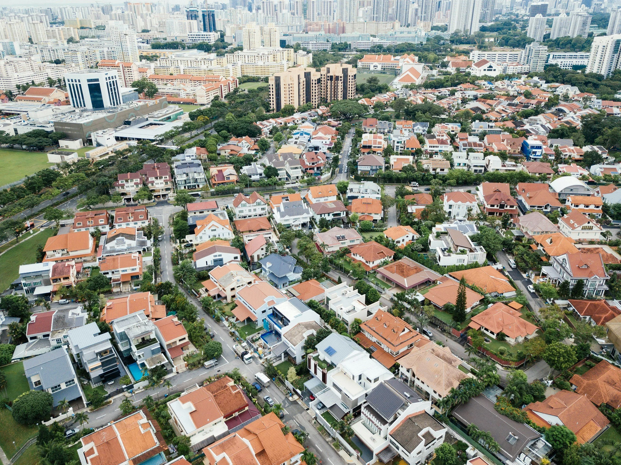 Aerial view of a residential neighborhood with single-family homes and tall buildings in the background.