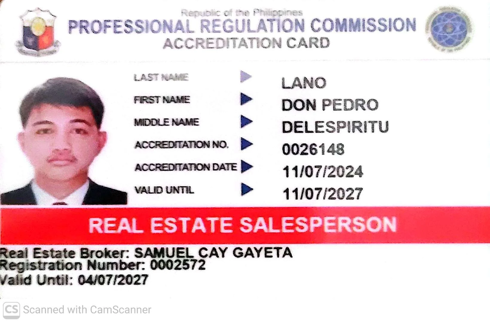 Photograph of a man with short dark hair, wearing a suit and tie, on an accreditation card from the Philippines' Professional Regulation Commission. The card displays personal details, an ID number, issue and expiry dates, and is labeled for a real estate salesperson. It also has official logos in the top corners.
