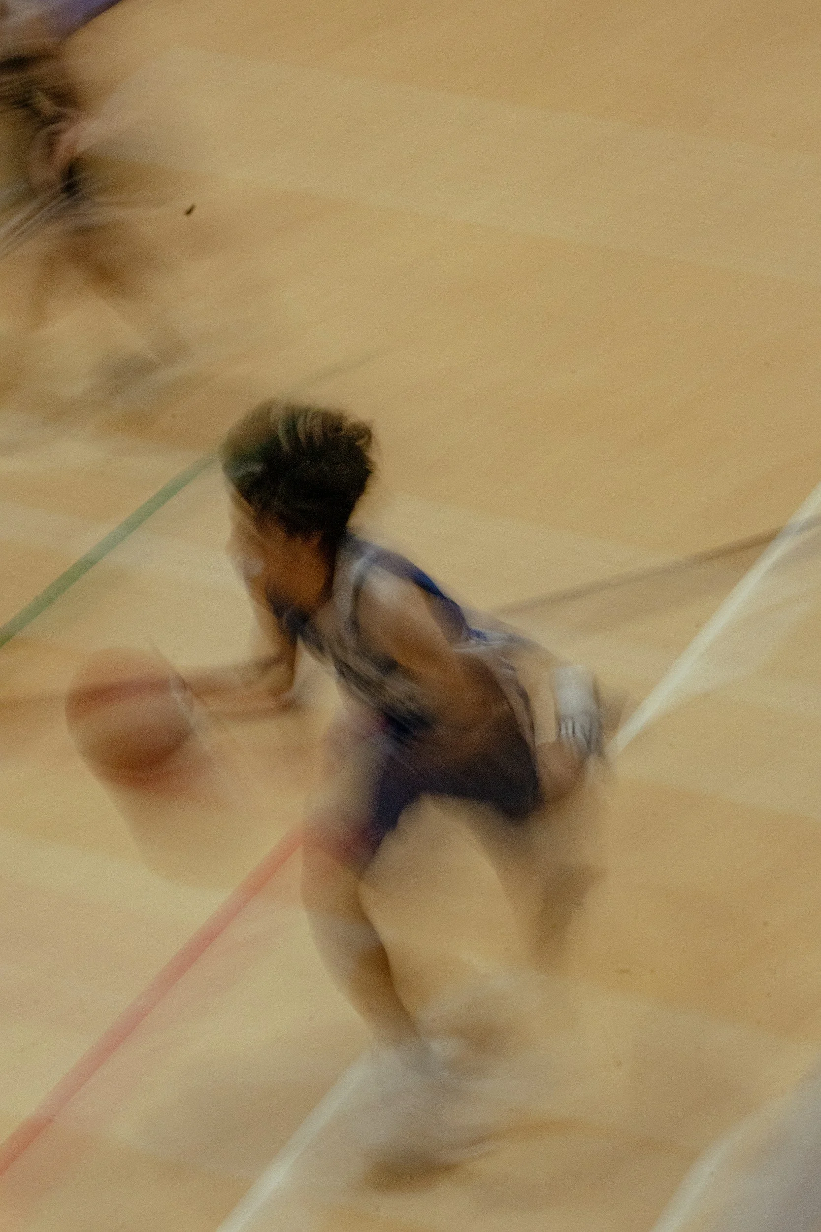 A young basketball player diving for a loose ball on the court during a game.