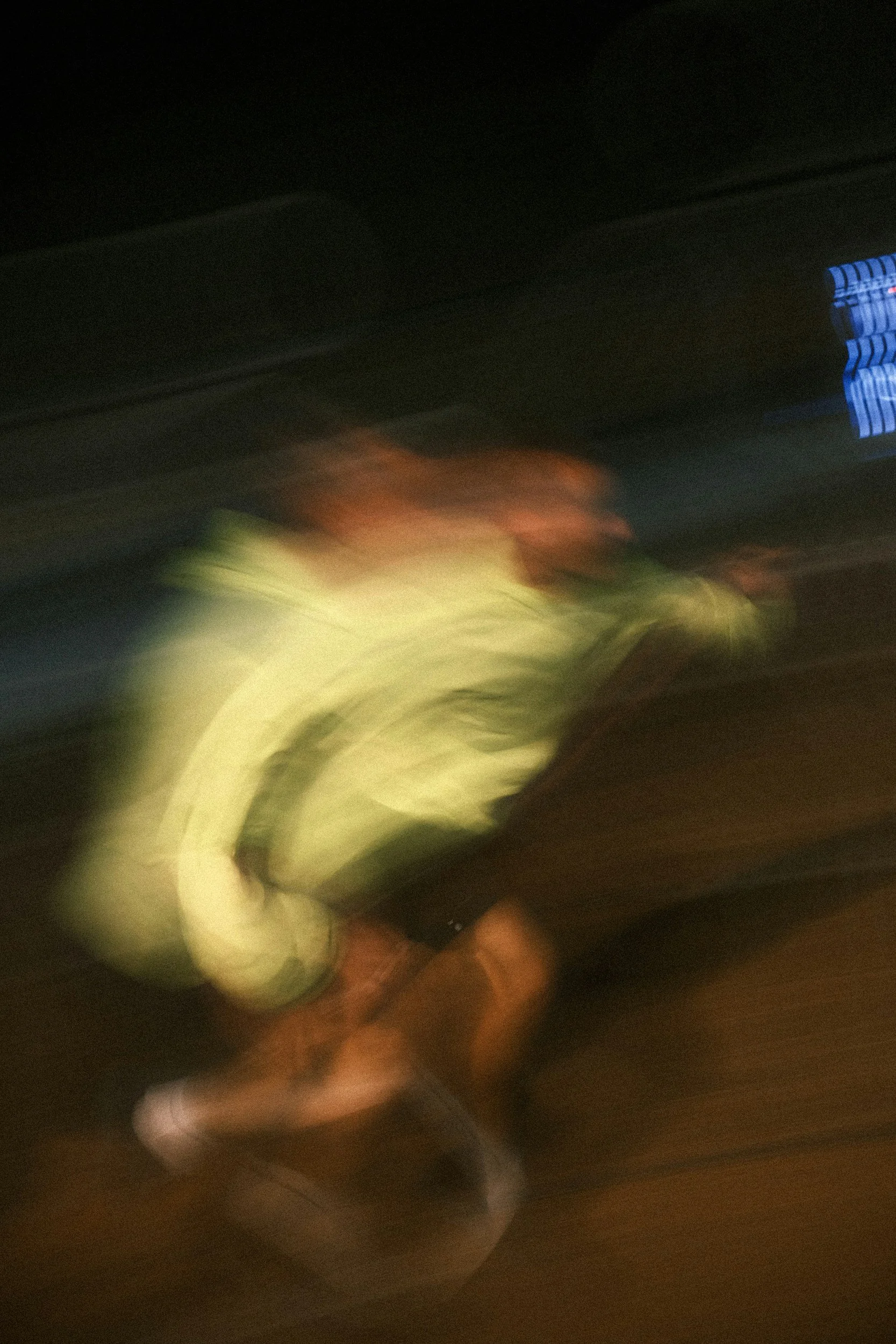 A person wearing a reflective safety vest and a red cap is walking or running on a street at night, captured in motion blur.