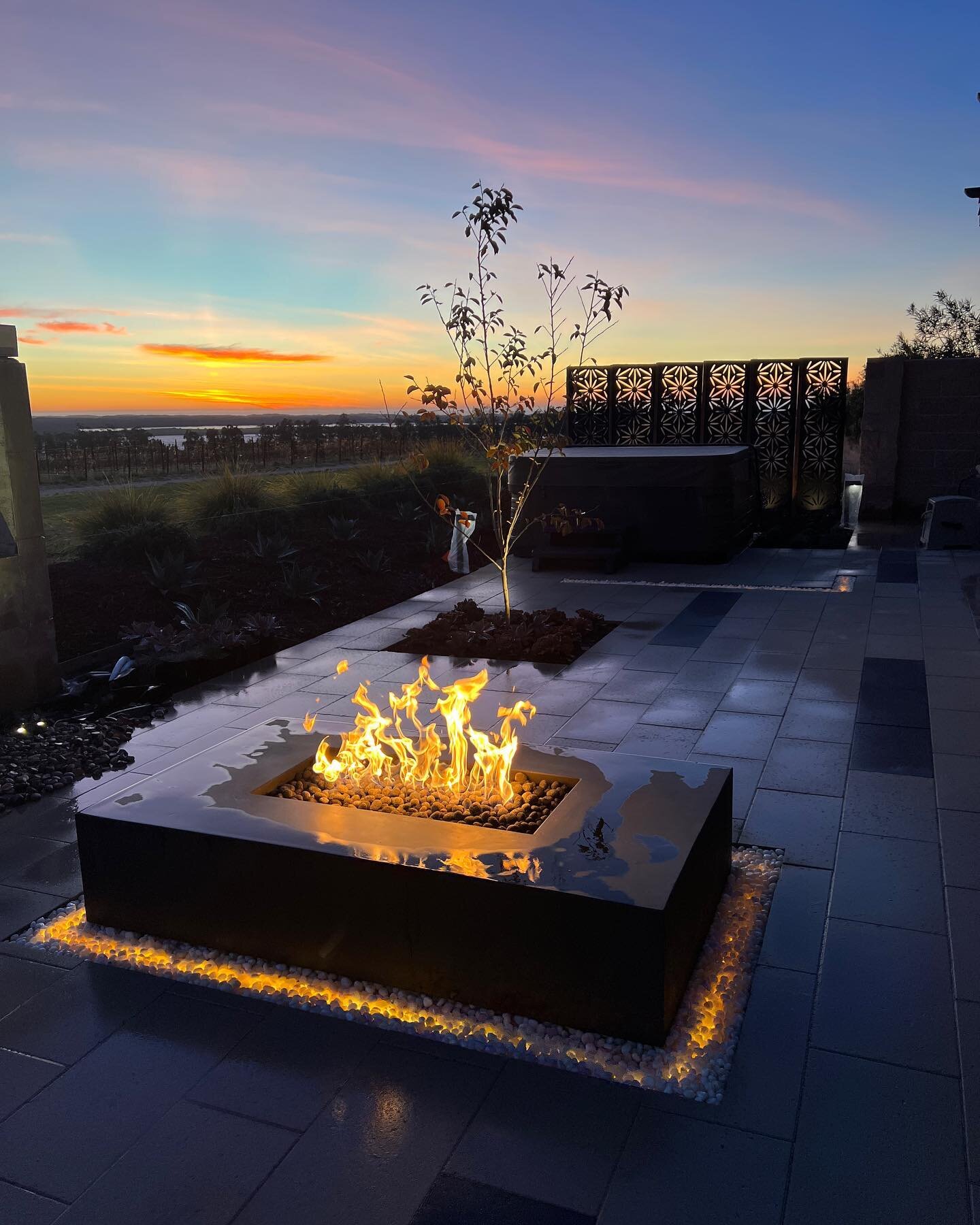 Scappaticci Project: Create a luxurious outdoor oasis with our latest project featuring a three spillway water feature, inground LED lighting, fire pit, privacy panels, and high-end pottery. This stunning design adds a touch of sophistication to any 