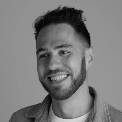 Smiling man with a beard in a denim jacket, black and white photo