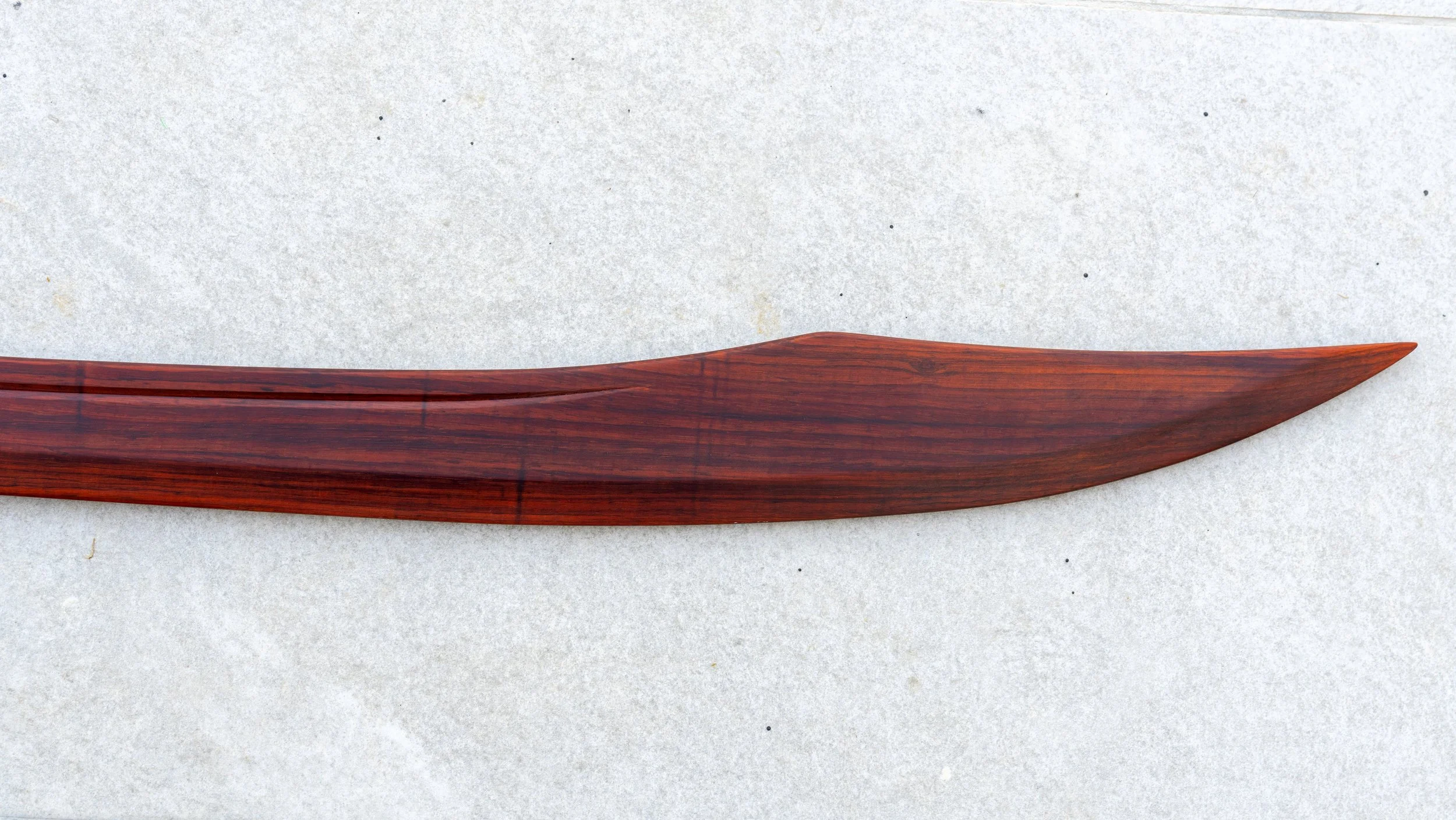 Curved red sandalwood Dao blade showing the fuller, natural wood grain and upswept tip