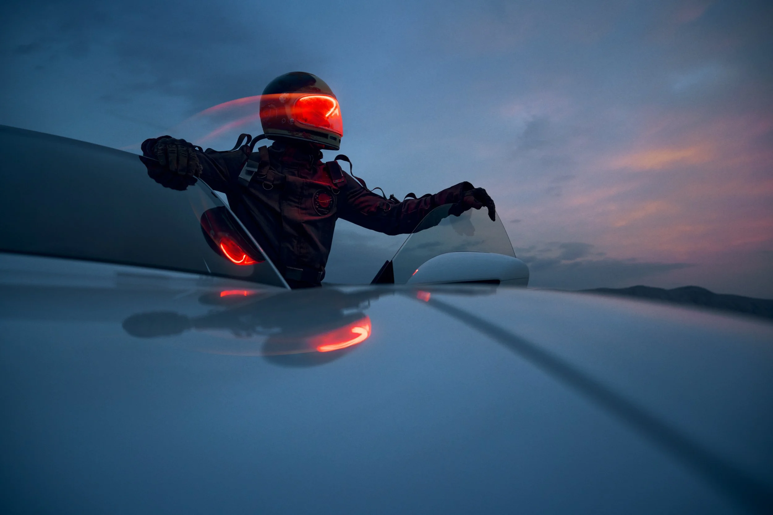 High-end automotive image of a white electric SUV on rocky desert terrain at dusk, showcasing cinematic lighting and professional retouching.
