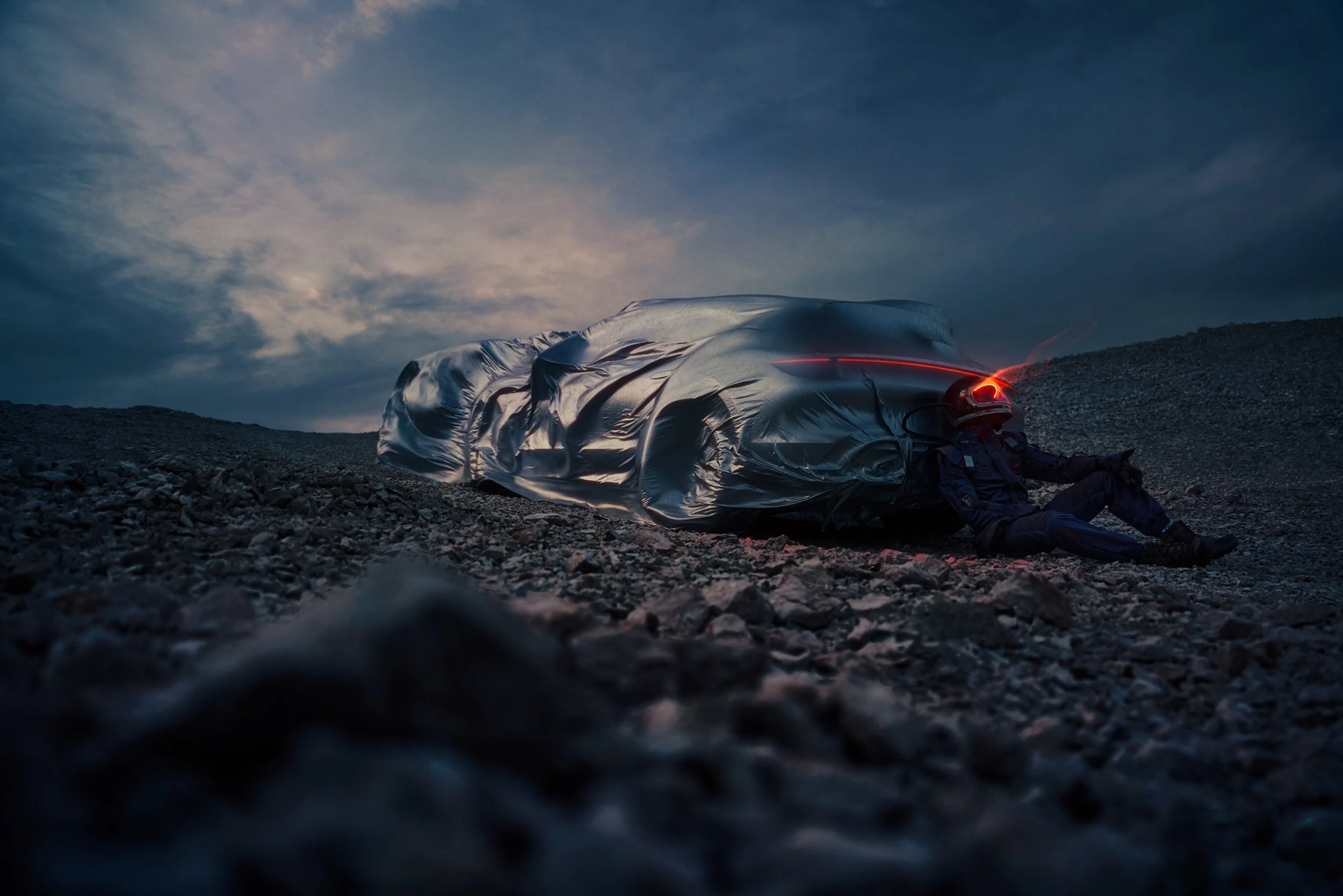 High-end automotive image of a white electric SUV on rocky desert terrain at dusk with dramatic skies, showcasing cinematic lighting and professional retouching.