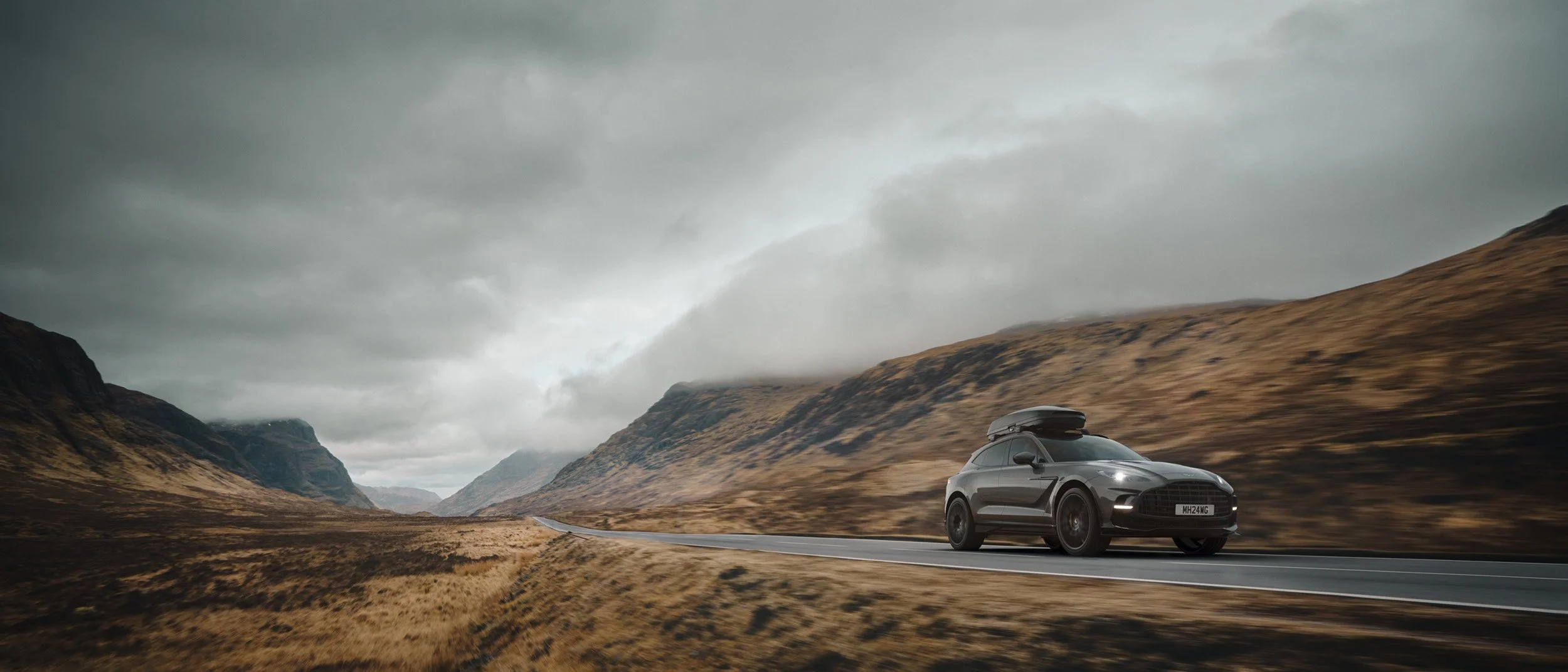 Photoreal automotive CGI scene of a luxury SUV in a rugged mountain landscape with cinematic lighting, demonstrating high-end compositing, retouching, and post-production for automotive advertising.