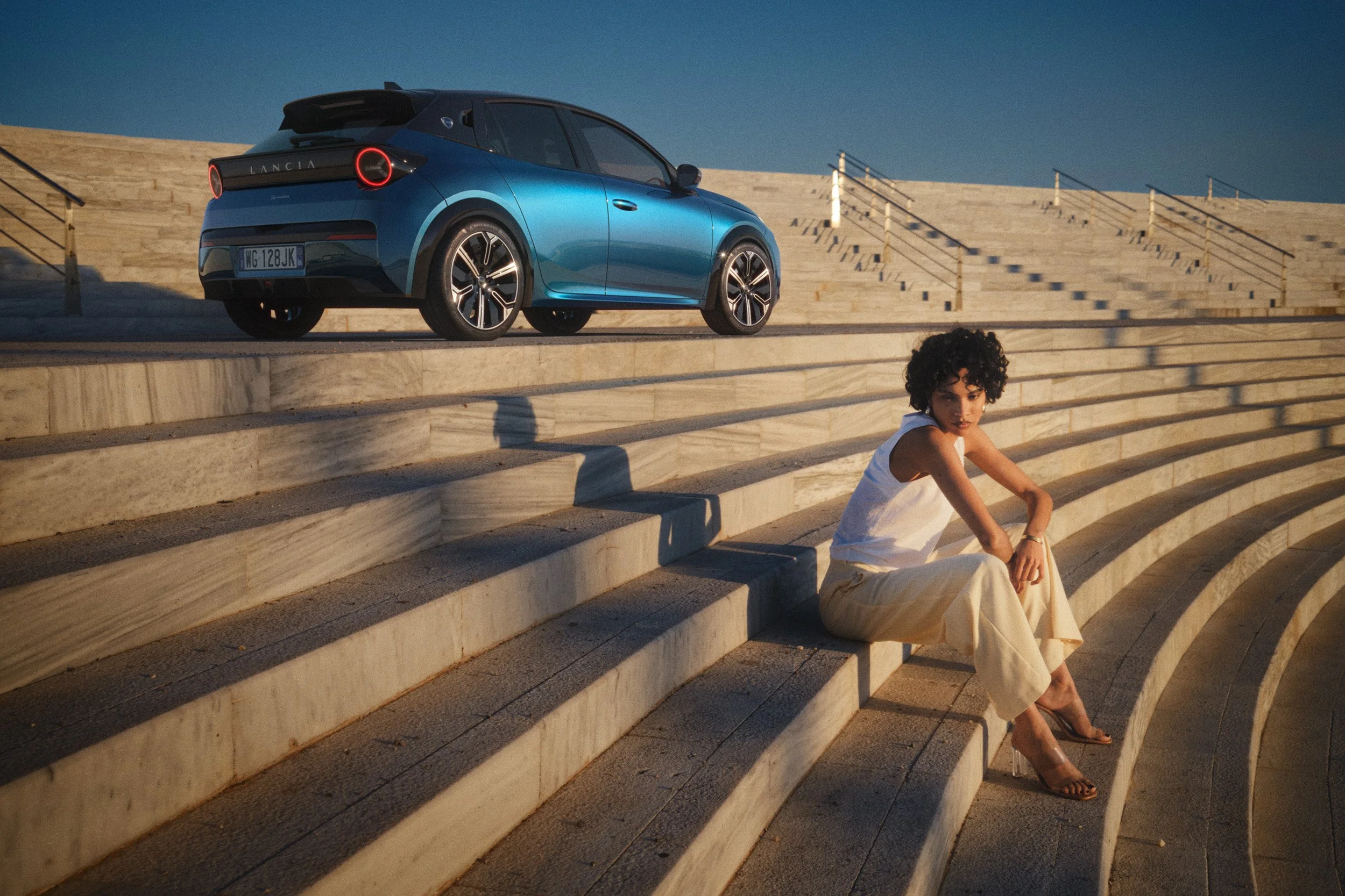 Automotive advertising image of woman on steps with Lancia Ypsilon. Automotive photography, CGI, retouching, postproduction