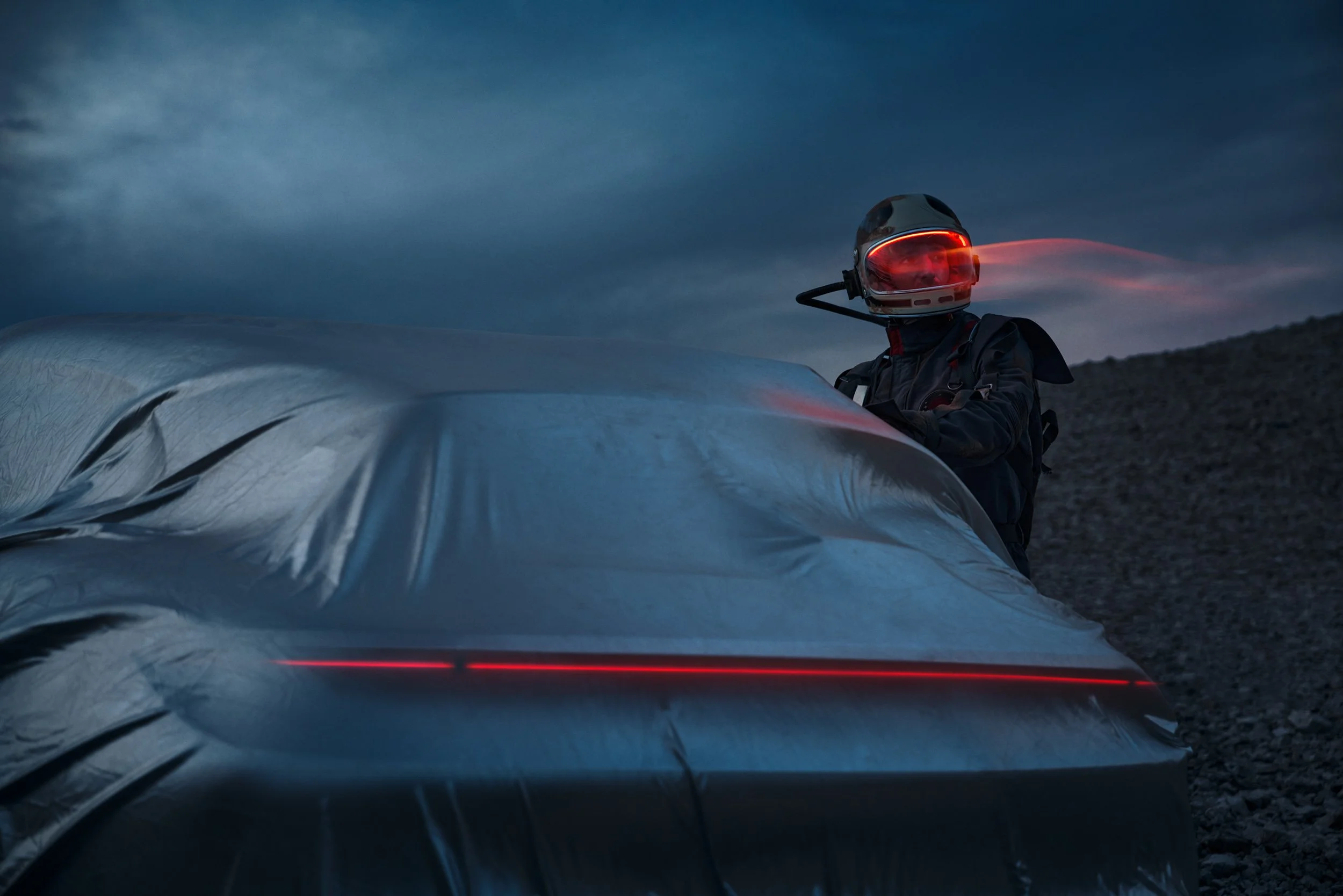 High-end automotive image of a white electric SUV on rocky desert terrain at dusk, showcasing cinematic lighting and professional retouching.