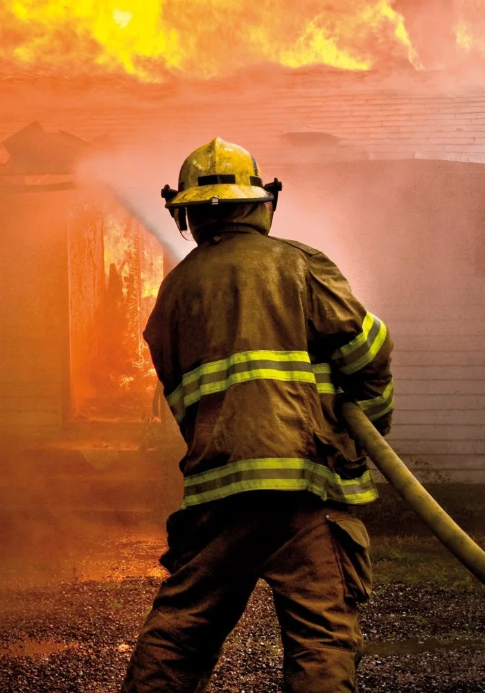 Firefighter responding to a building fire illustrating the importance of passive fire protection systems in construction