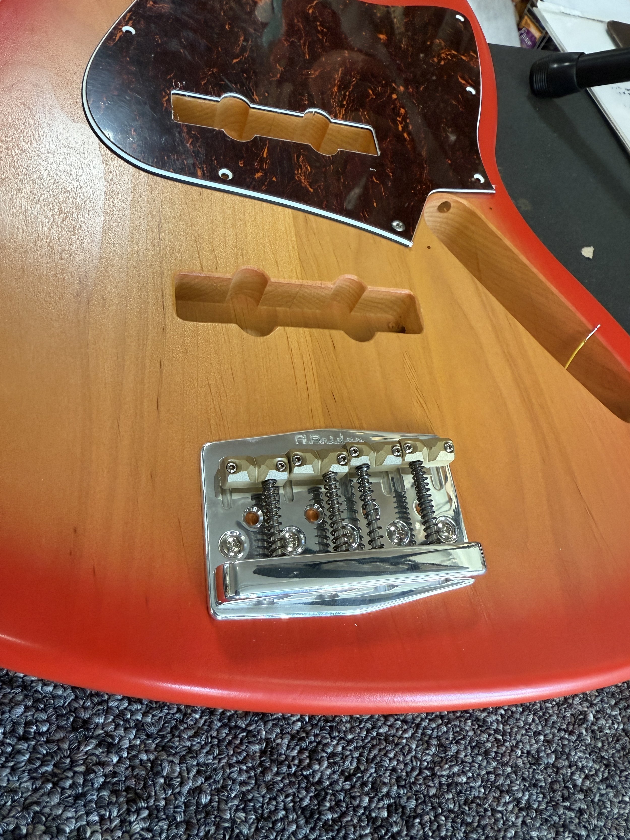 Disassembled electric guitar with the strings and pickguard removed, showing the bridge and body.