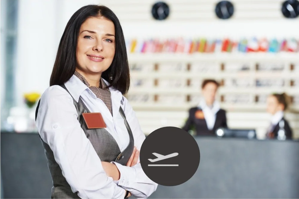 An Altura airport concierge in a grey vest and patterned scarf, with an aircraft departure icon