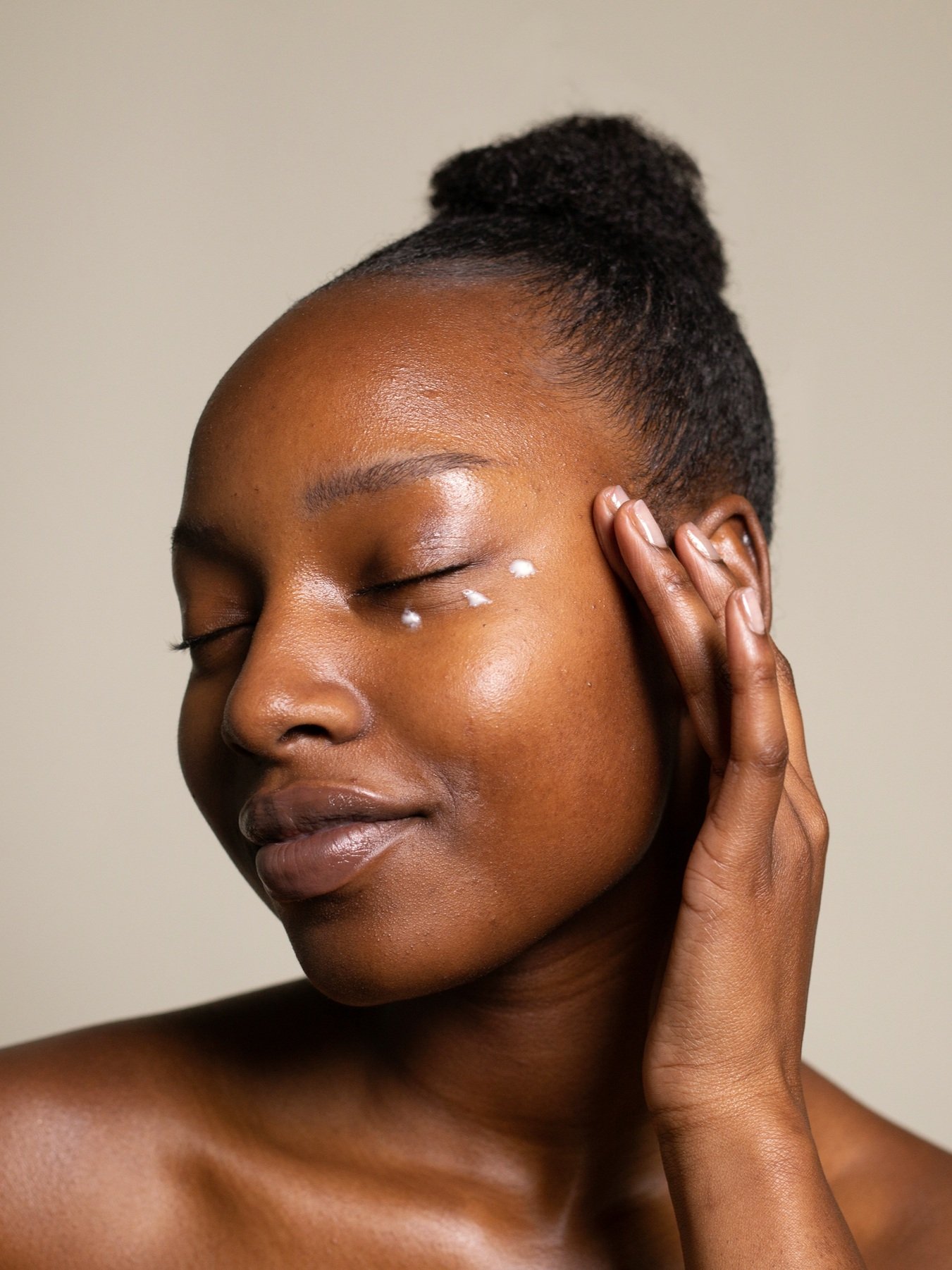 Black model with 3 dots of eye cream under her eye. Skincare Dr Sams Design Creative Lead