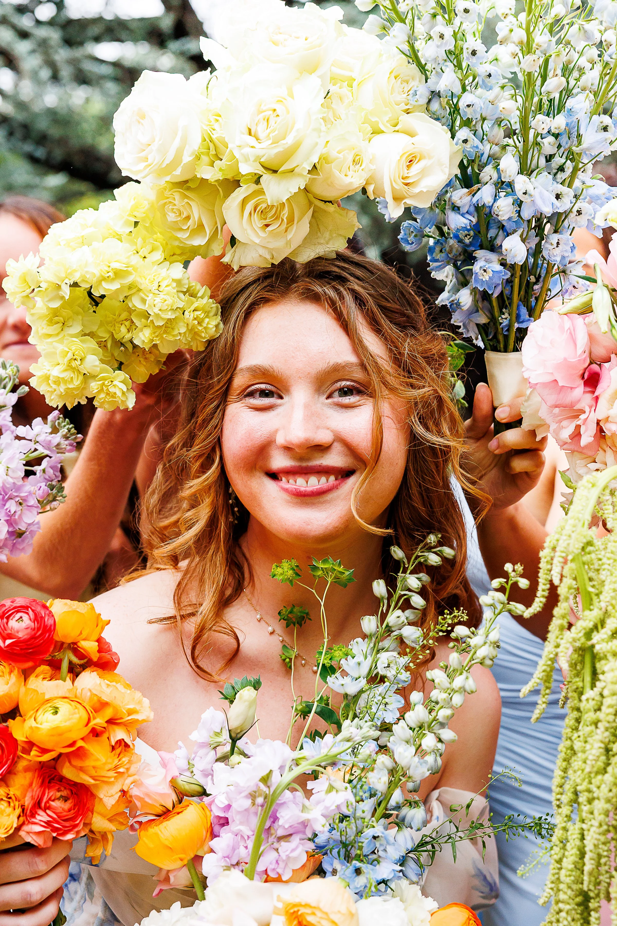Smiling woman surrounded by colorful flowers during a celebration or event.