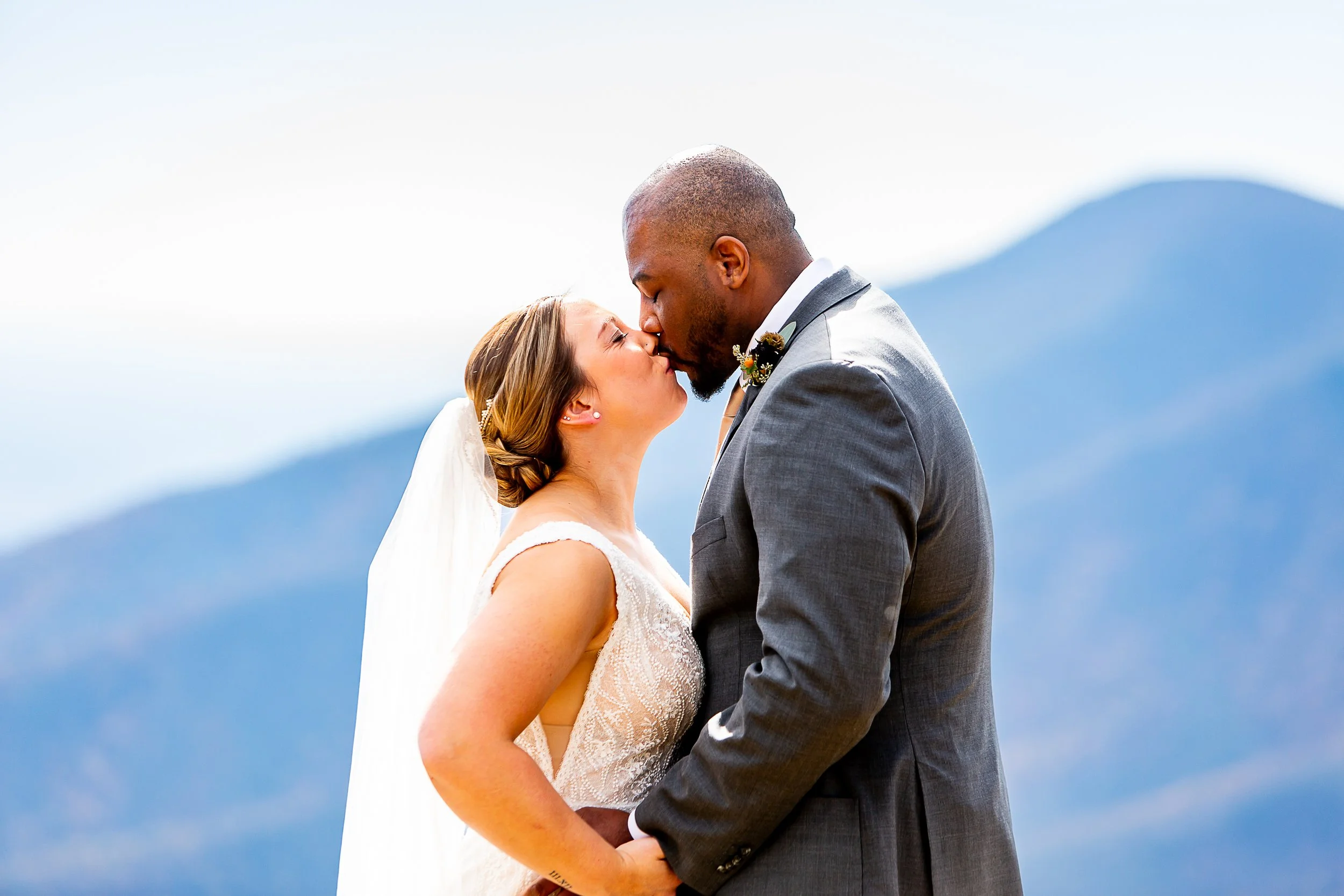 bride and groom share a kiss with a mountain backdrop