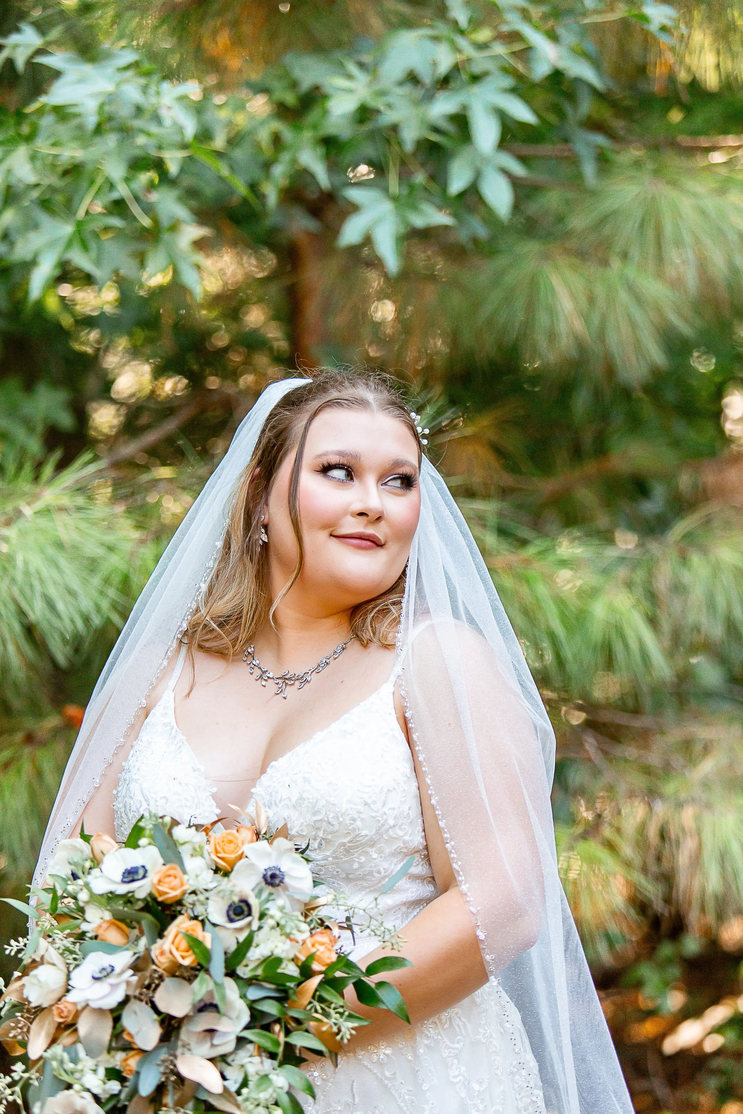 bride in veil poses with pastel bouquet