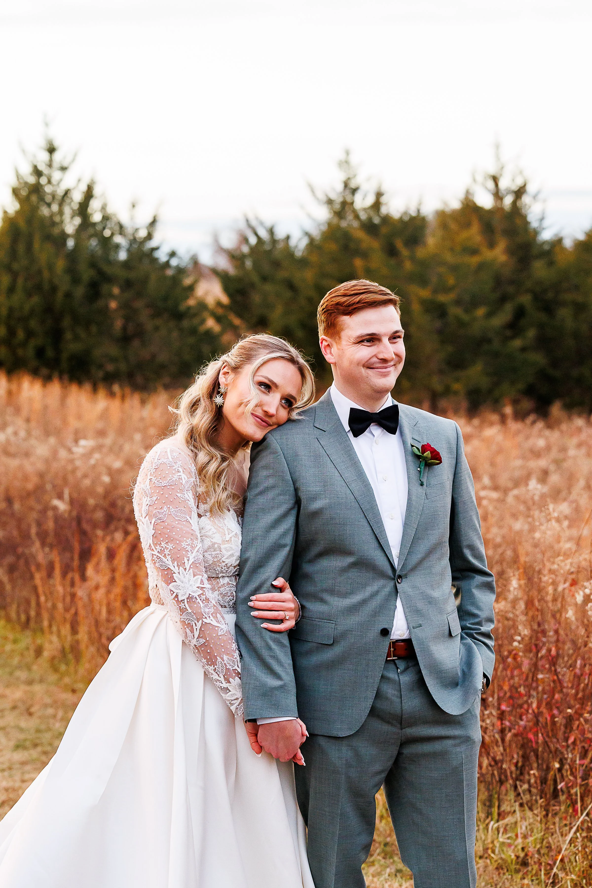 Bride in a lace-sleeved gown resting her head on her groom's shoulder in a golden autumn field at 48 Fields Farm in Leesburg, VA.