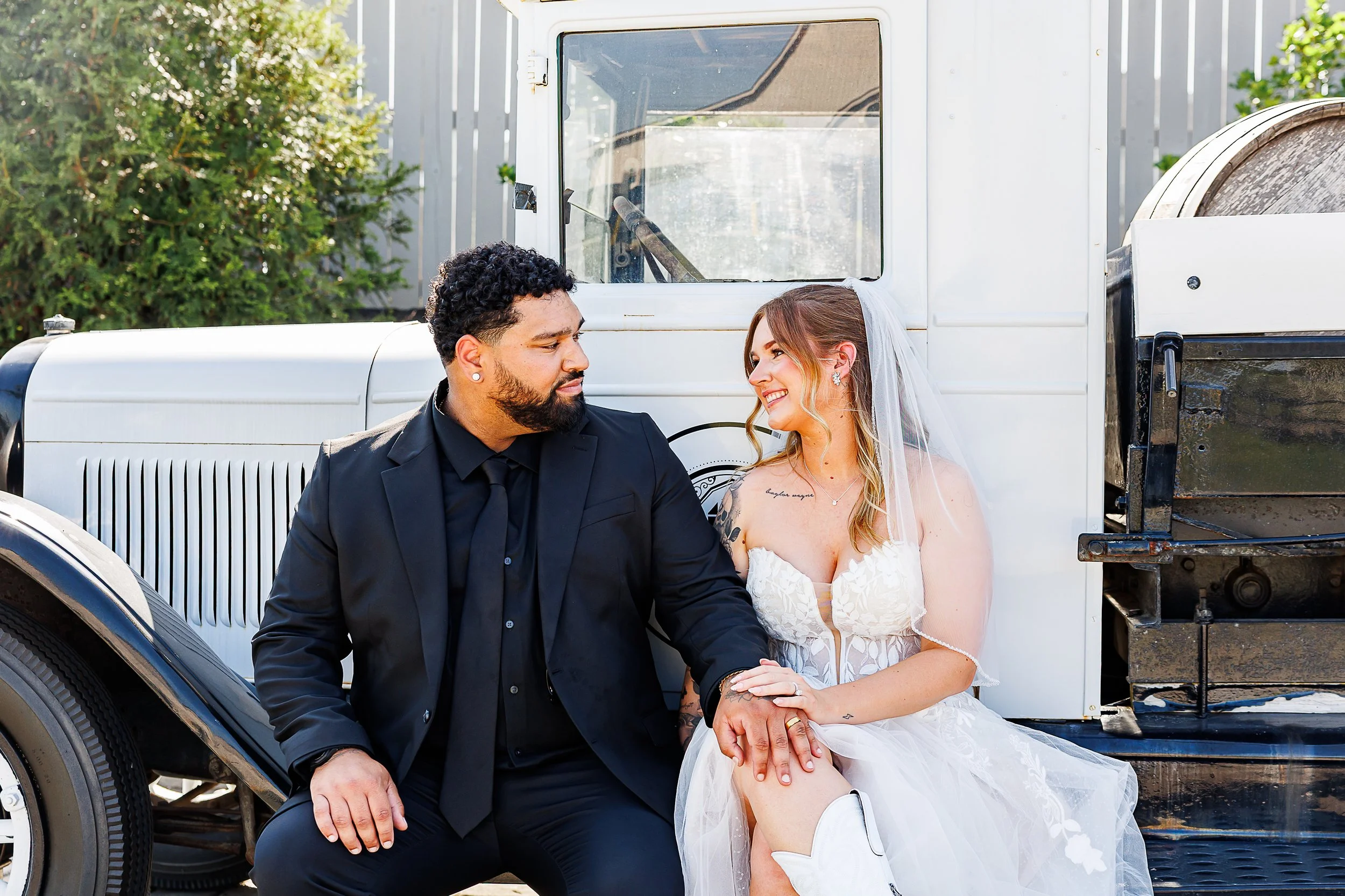 Bride in a lace bodice gown and white cowboy boots staring into the groom's eyes while sitting on a vintage truck at Diamond Farm and Brewery in Nokesville, VA.