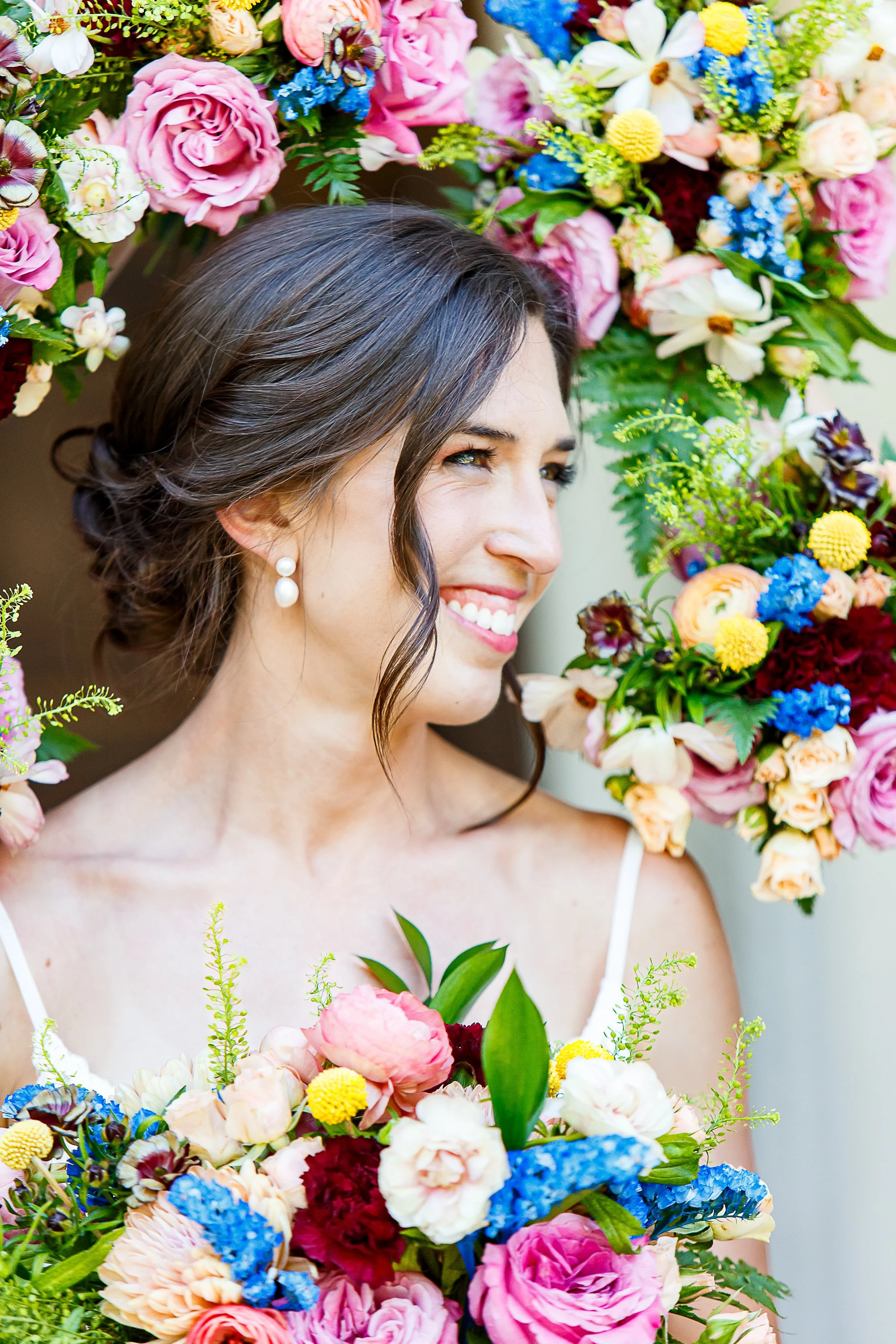 bride smiling, surrounded by frame of bridesmaid bouquets