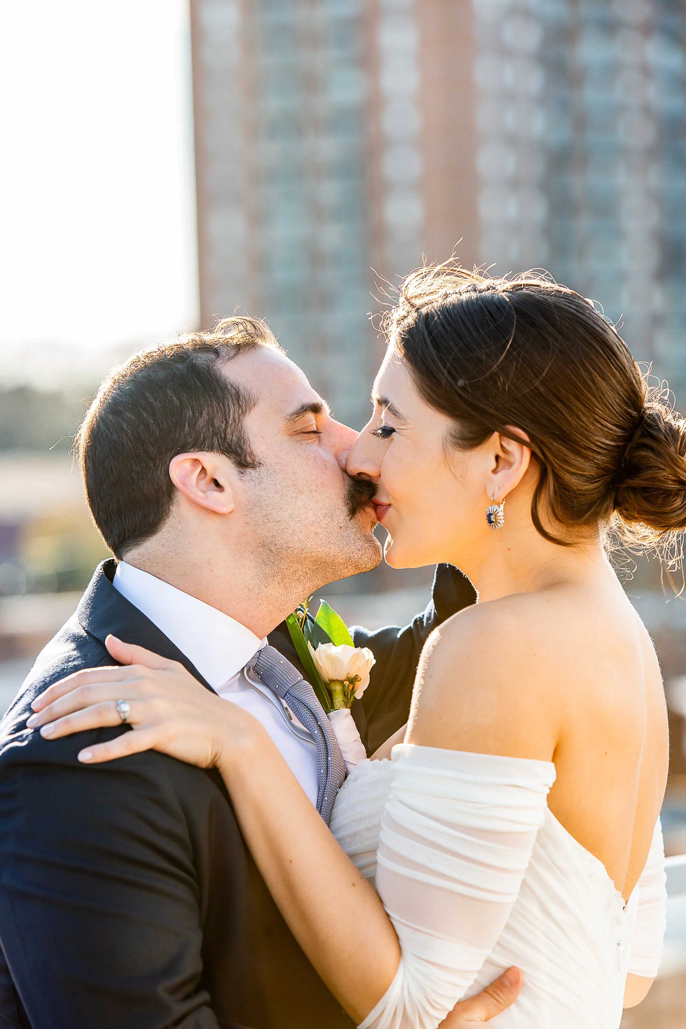 bride and groom kissing with buildings in the background, rooftop view