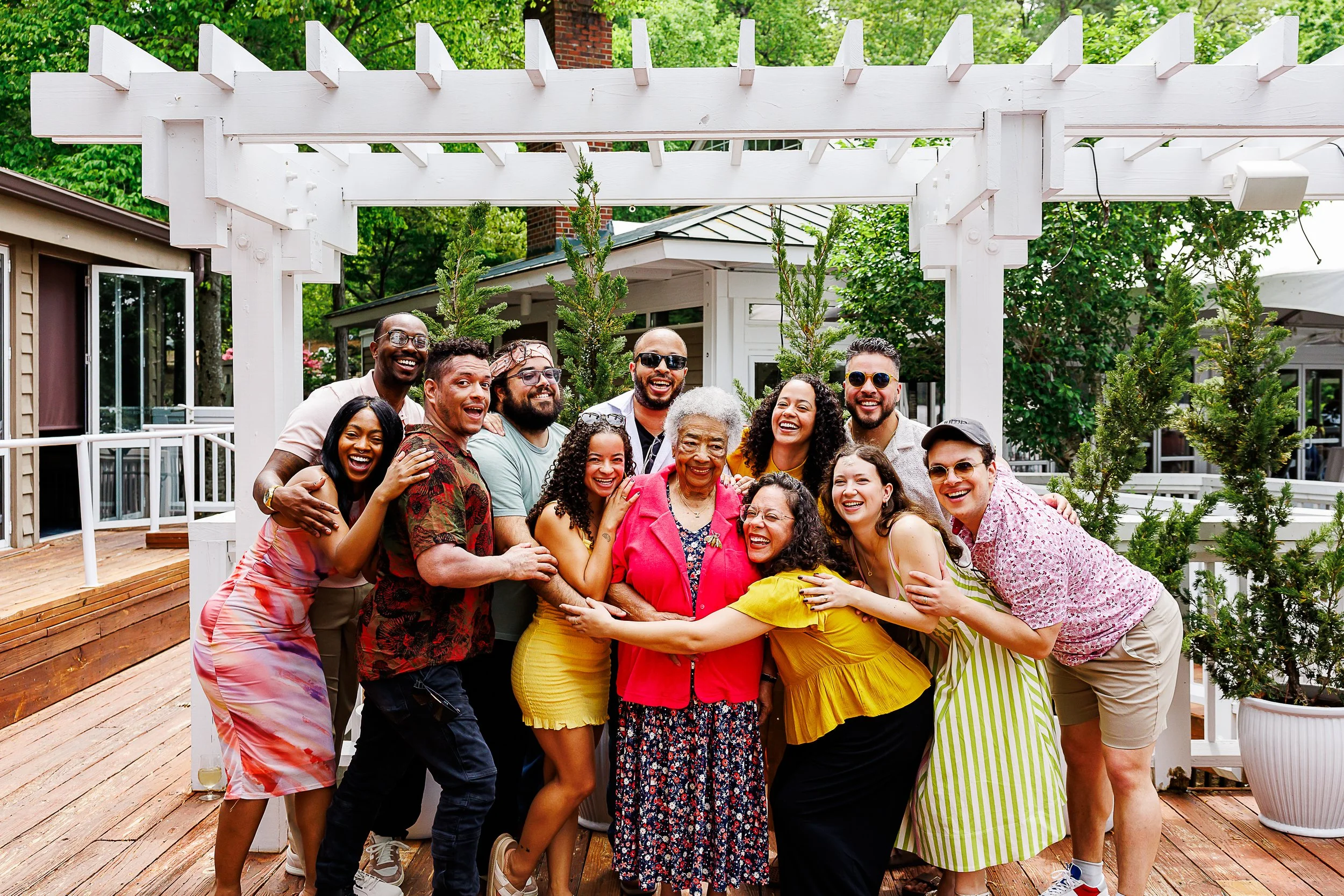Photographer capturing a candid photo of a large group posed together outdoors in a garden setting with brick pavers and lush greenery, Richmond, VA