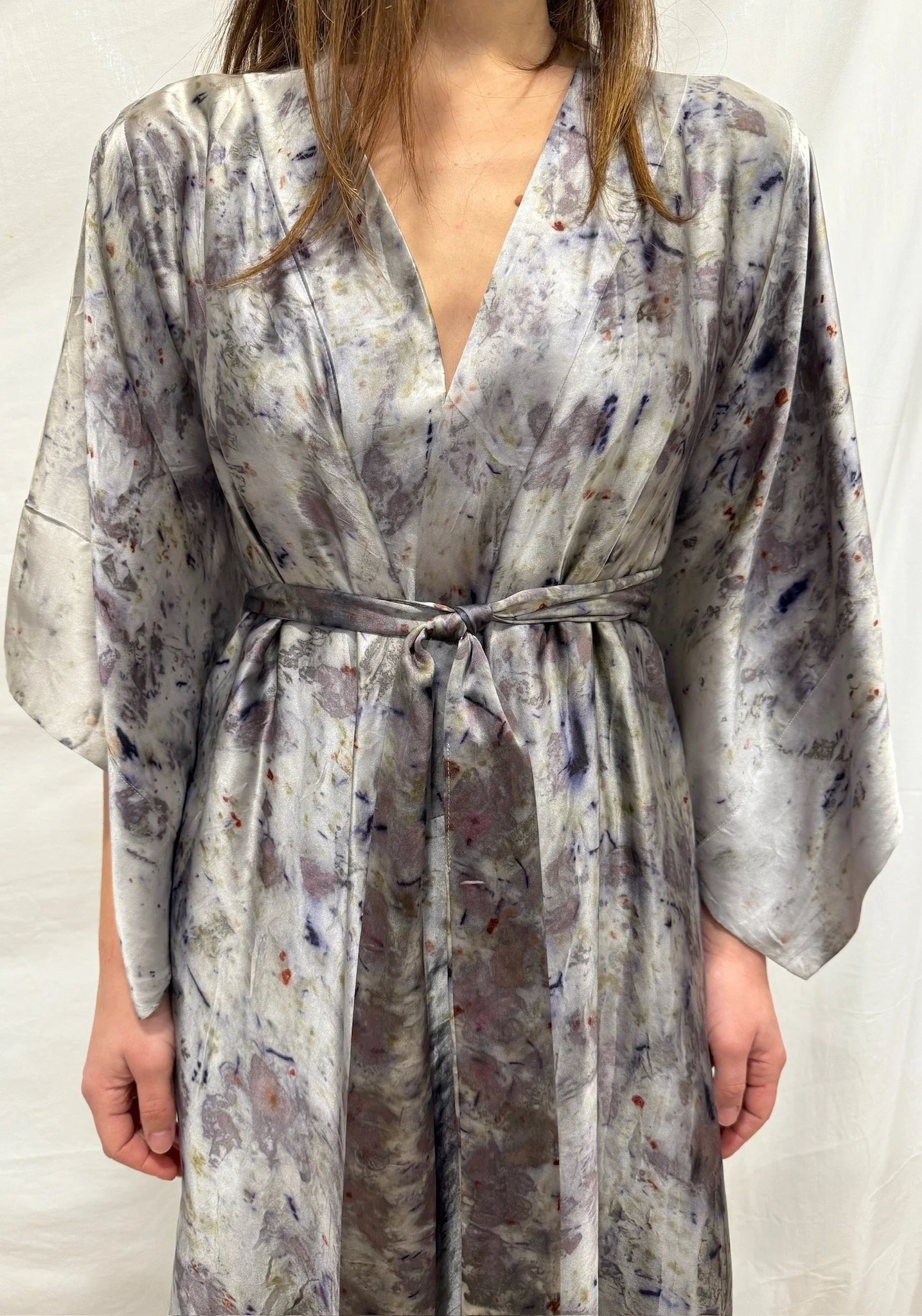 Person wearing a long, silk, naturally dyed silk kimono/ robe with a V-neck and a tie at the waist. One of a kind.