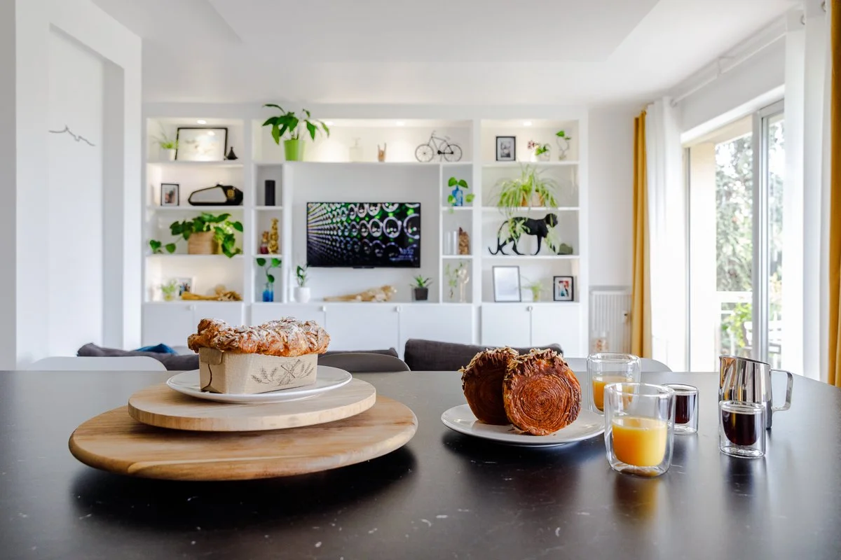Intérieur chic et accueillant : Table garnie de viennoiseries, salon verdoyant élégant