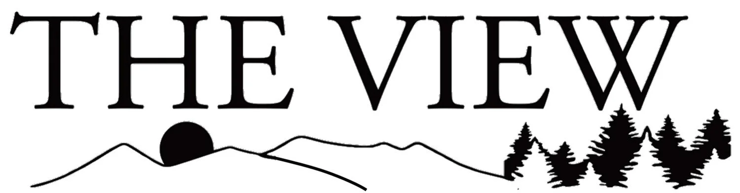 Text reads 'The View' with a silhouette of mountains, a sun setting, and pine trees in the background.